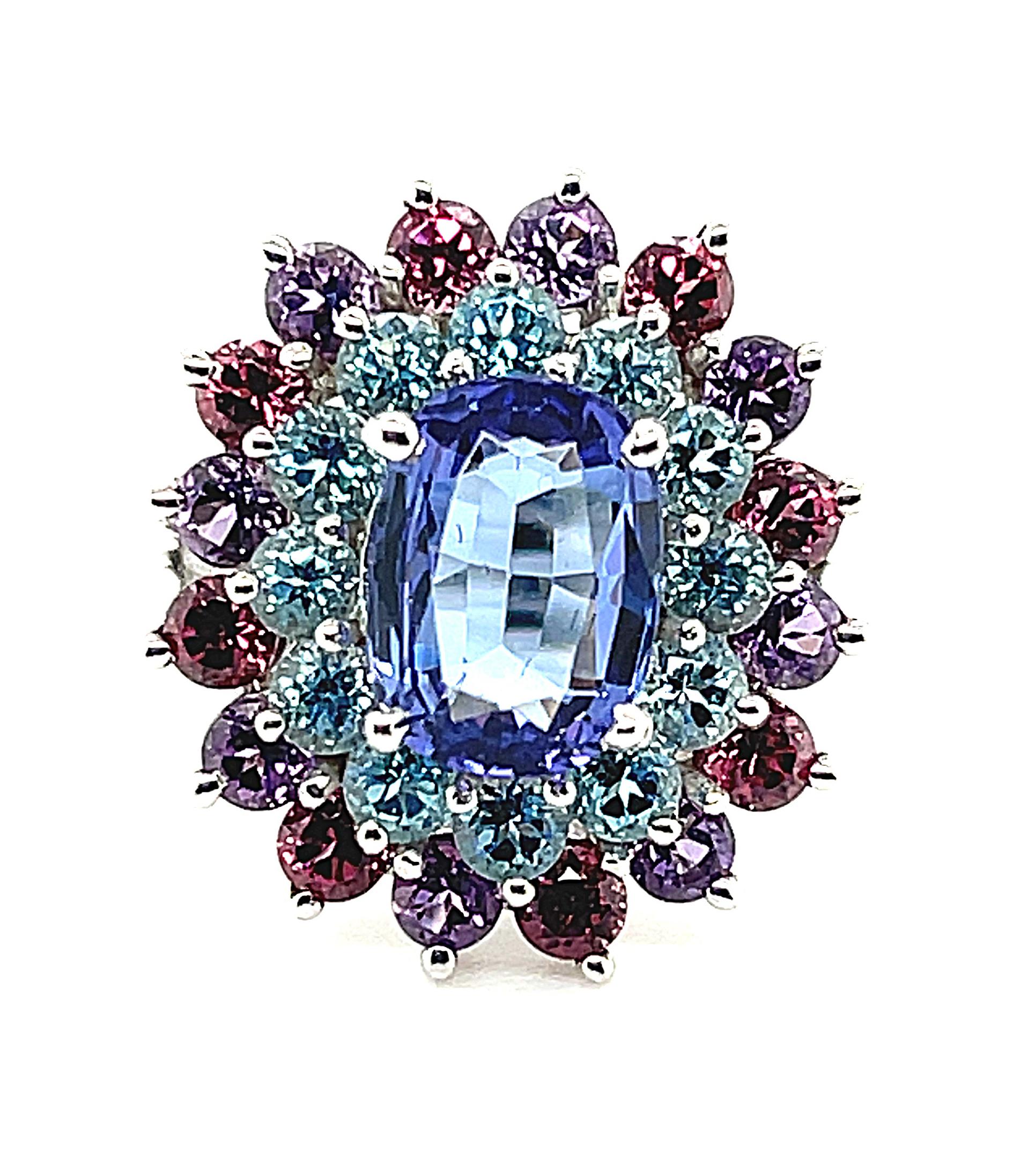 This one-of-a-kind ring uses color in an almost painterly way, combining rich tanzanite and brilliant blue topazes with rosy rhodolite garnets and bright purple amethysts! The center tanzanite is a beautiful periwinkle shade, perfectly highlighted