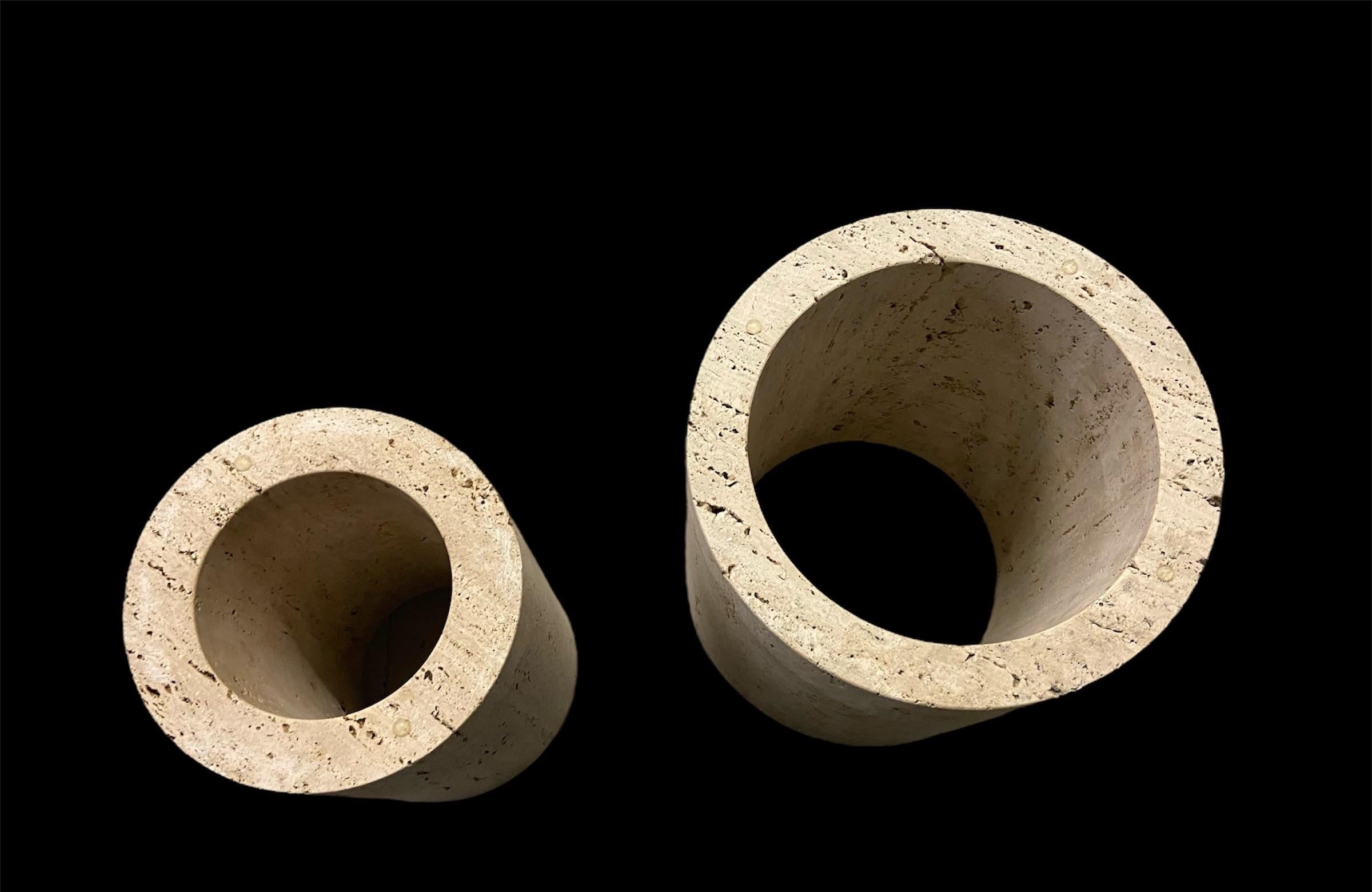 2 Cilindri aperti in travertino, basi per tavolini da caffè, cachepot o sculture, italiani, anni '70.
Entrambi hanno la stessa altezza e quello piccolo si inserisce in quello più grande per la spedizione. 
La più grande misura 33 cm di diametro