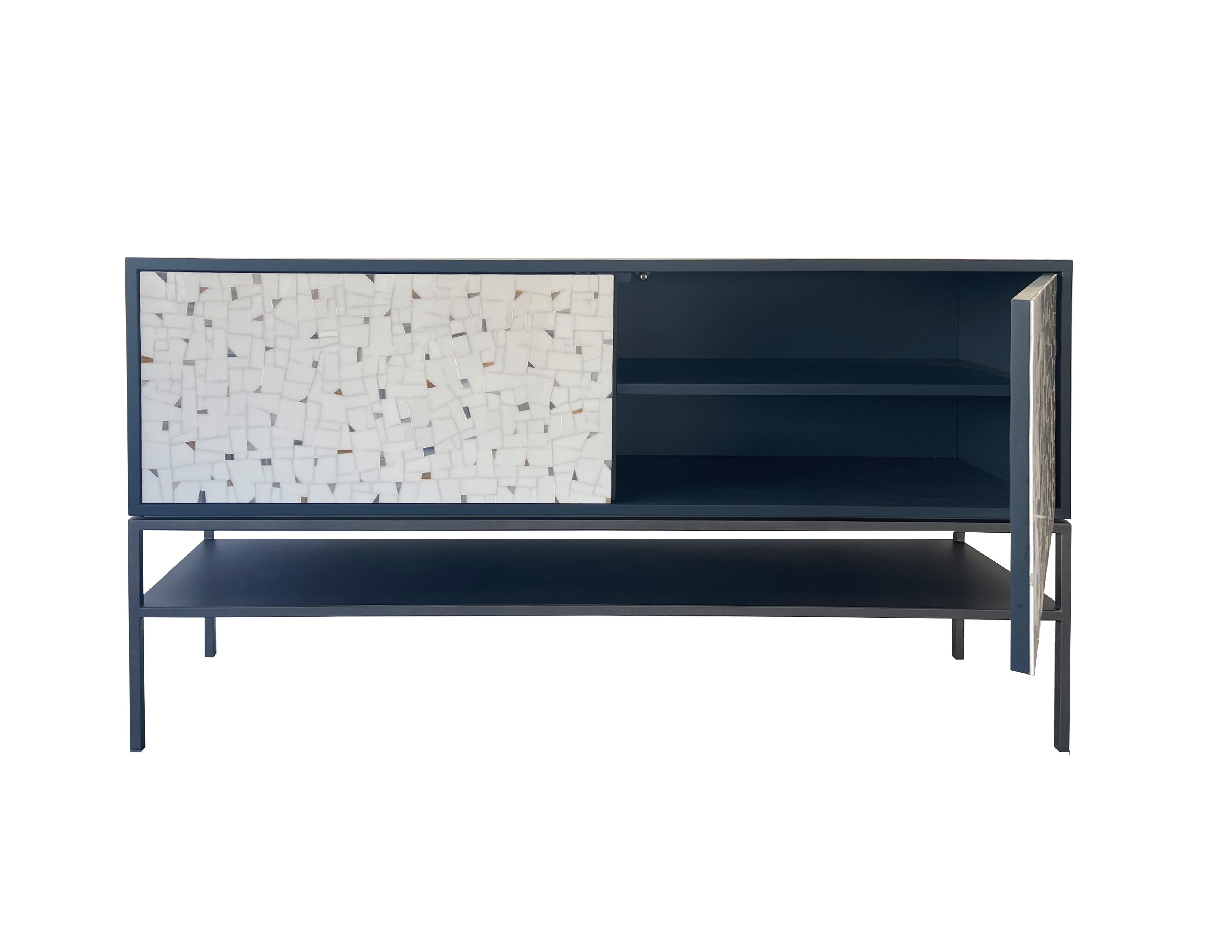 Our 2- door serving buffet by Ercole Home is a touch latch buffet in a custom deep blue matte wood finish. The smoothness of the wood contrasts perfectly with the glossy shine of the terrazzo patterned glass that adorns the front of each door. The