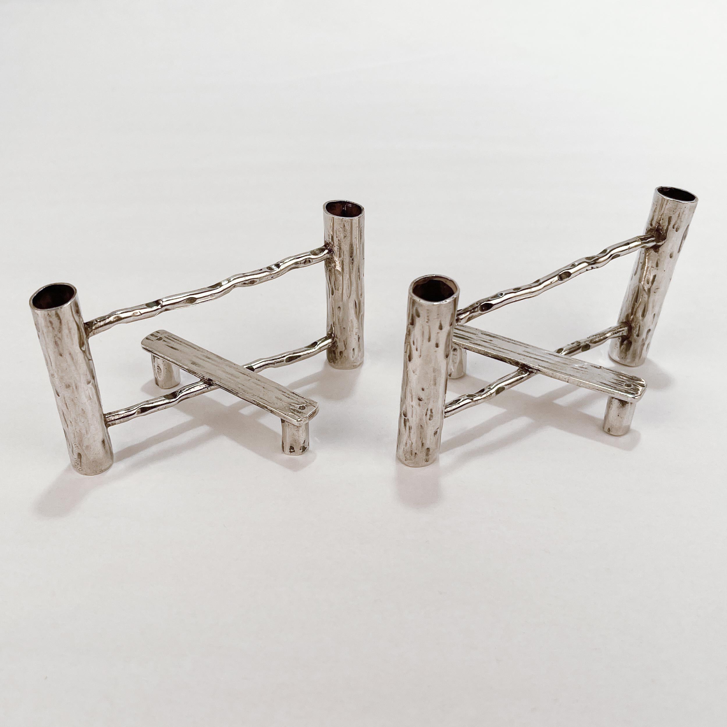 A fine pair of antique English sterling silver candle holders or small bud vases.

Made by J E Bushell of Birmingham, England. 

In the form of 2 split rail fences with attached benches. 

We assume that these function as taper-stick candle holders