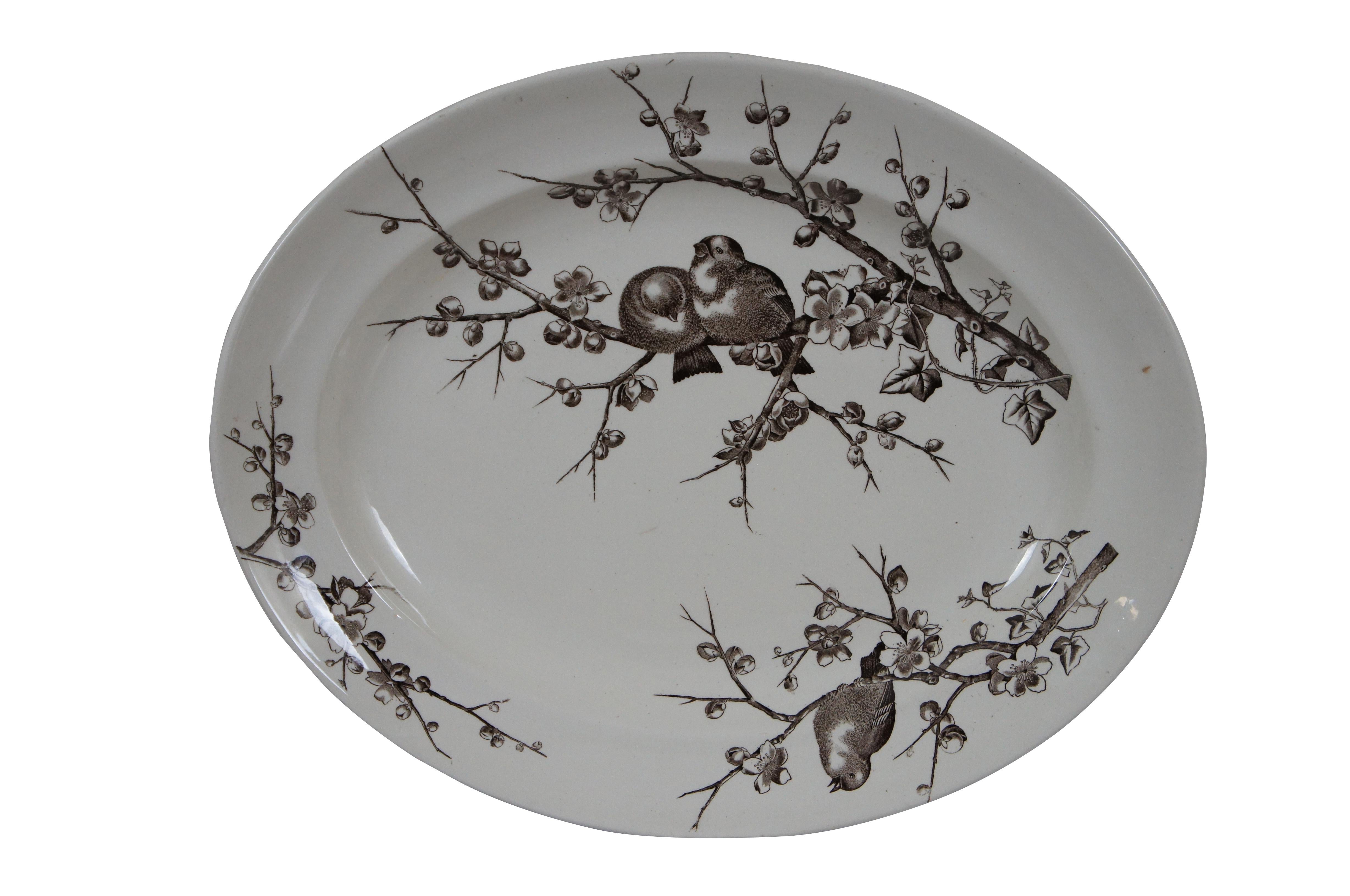 Pair of late 19th century brown transferware ceramic serving platters. One oval platter by George Jones & Sons in the Almonds pattern, showing a pair of birds perched on flowering almond branches. And one round platter by Alfred Meakin in Medway