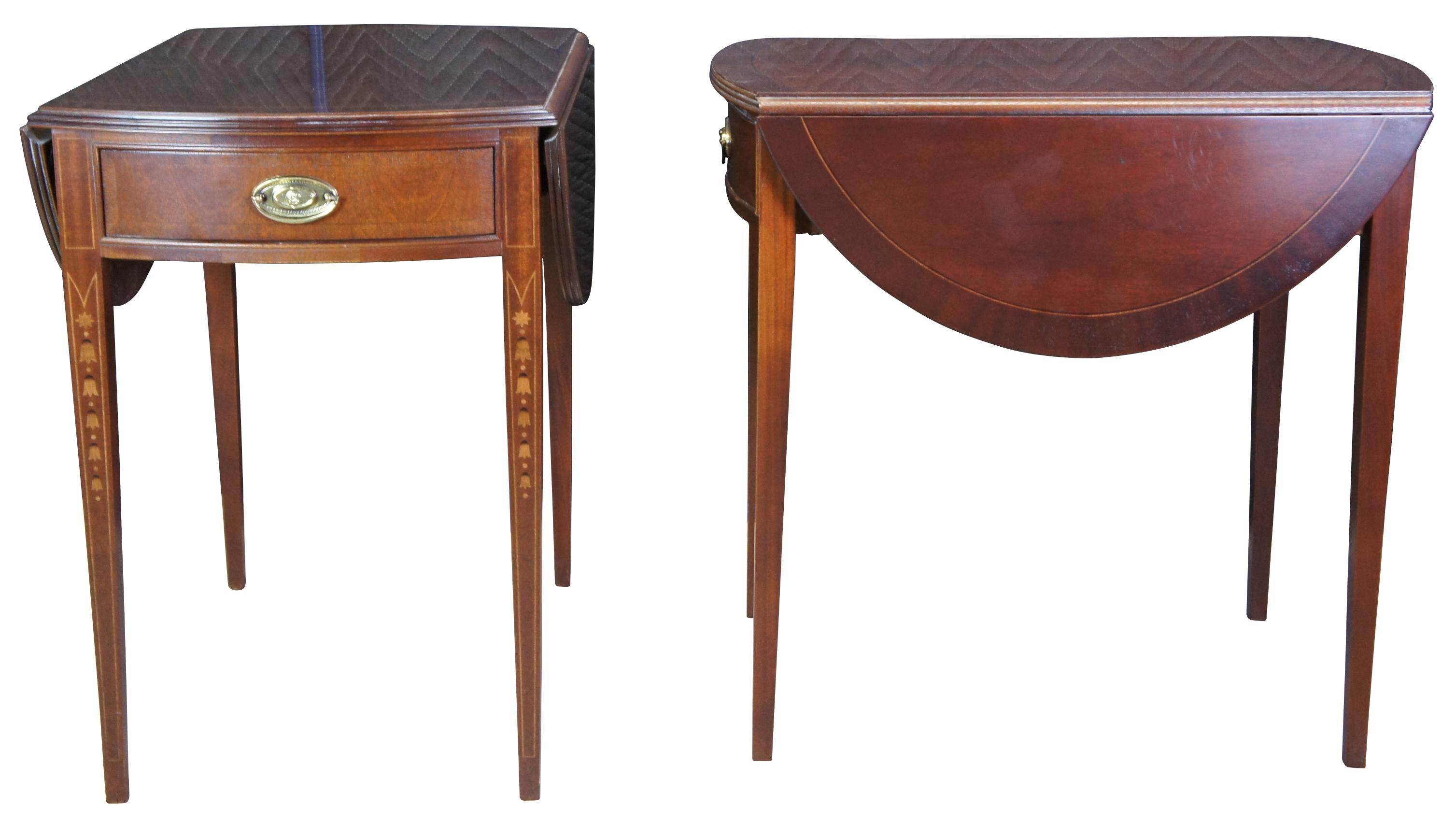 Pair of American Made Ethan Allen 18th century pembroke side tables, 22-8504. Made from mahogany with drop leafs that open to create an ovular surface. Features banding over square tapered legs, inlay, dovetailed drawers and brass hardware. Inspired