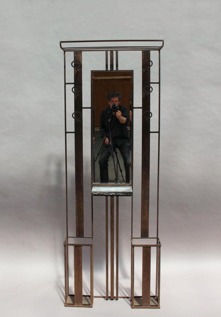 Two fine French Art Deco wrought iron coat racks with an umbrella and hat stands, a beveled mirror and a small marble shelf.