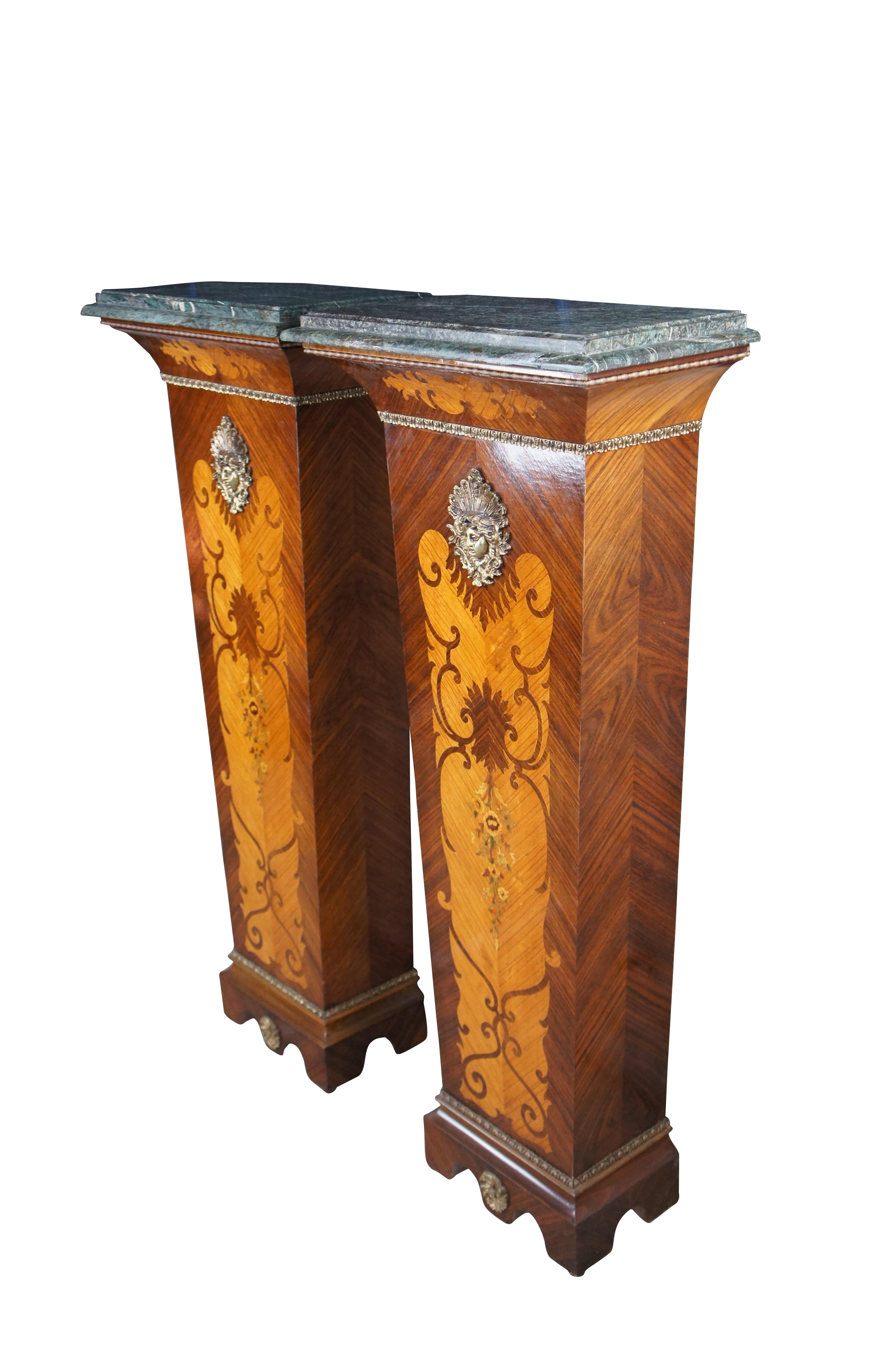Pair of two French Louis XV style sculpture stands or clock / bust pedestals.  Made of walnut and fruit wood featuring tapered form with inlaid matchbook walnut parquetry design and floral marquetry.  Each features a beveled green marble top, gilded