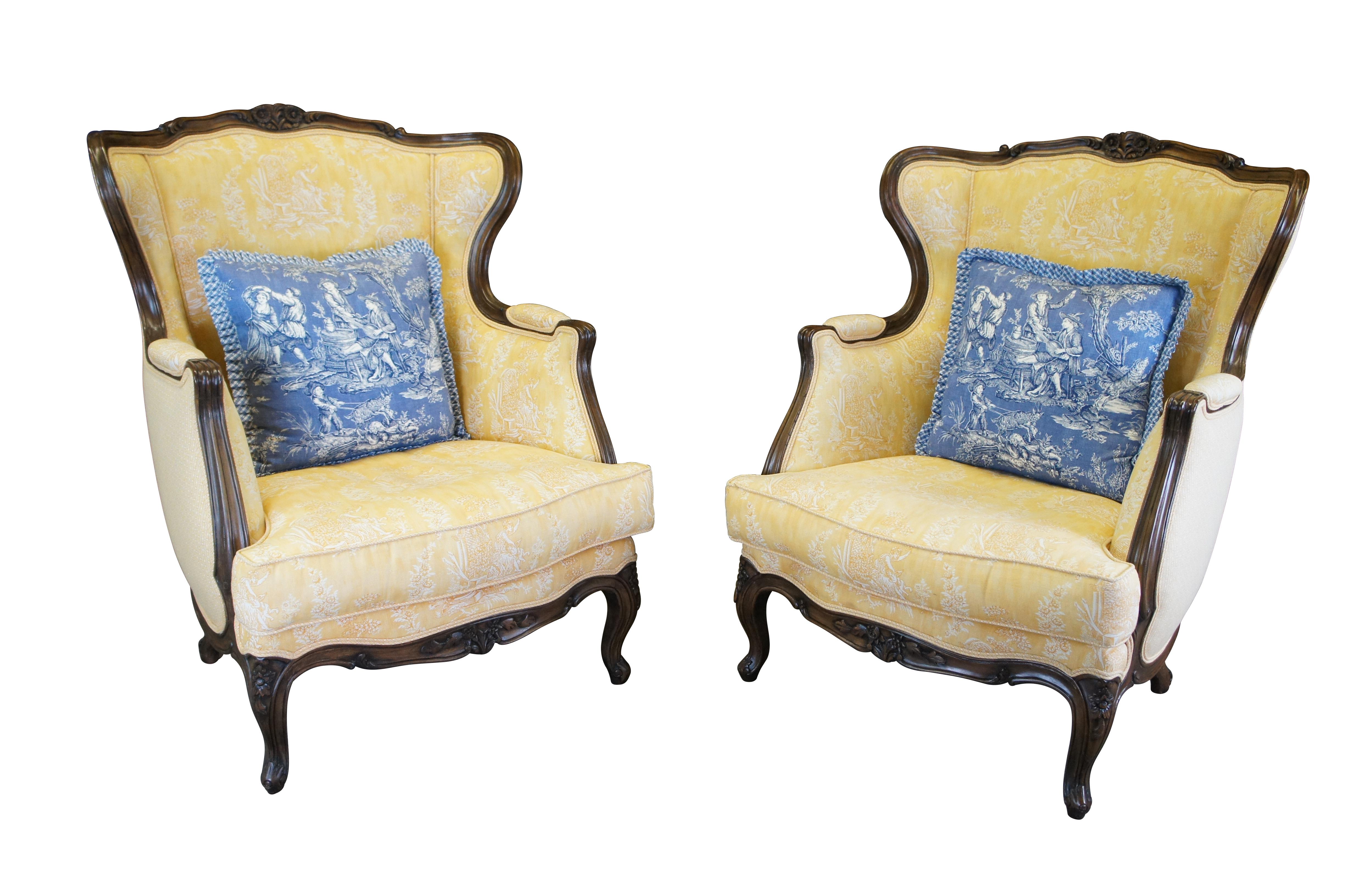 Two vintage French Louis XVI style club / lounge / library arm chairs.  Made of walnut featuring wingback design with high arms, carved with floral / foliate accents, Queen Anne legs, cabriole feet and tole upholstery with woman spanking a cherub /