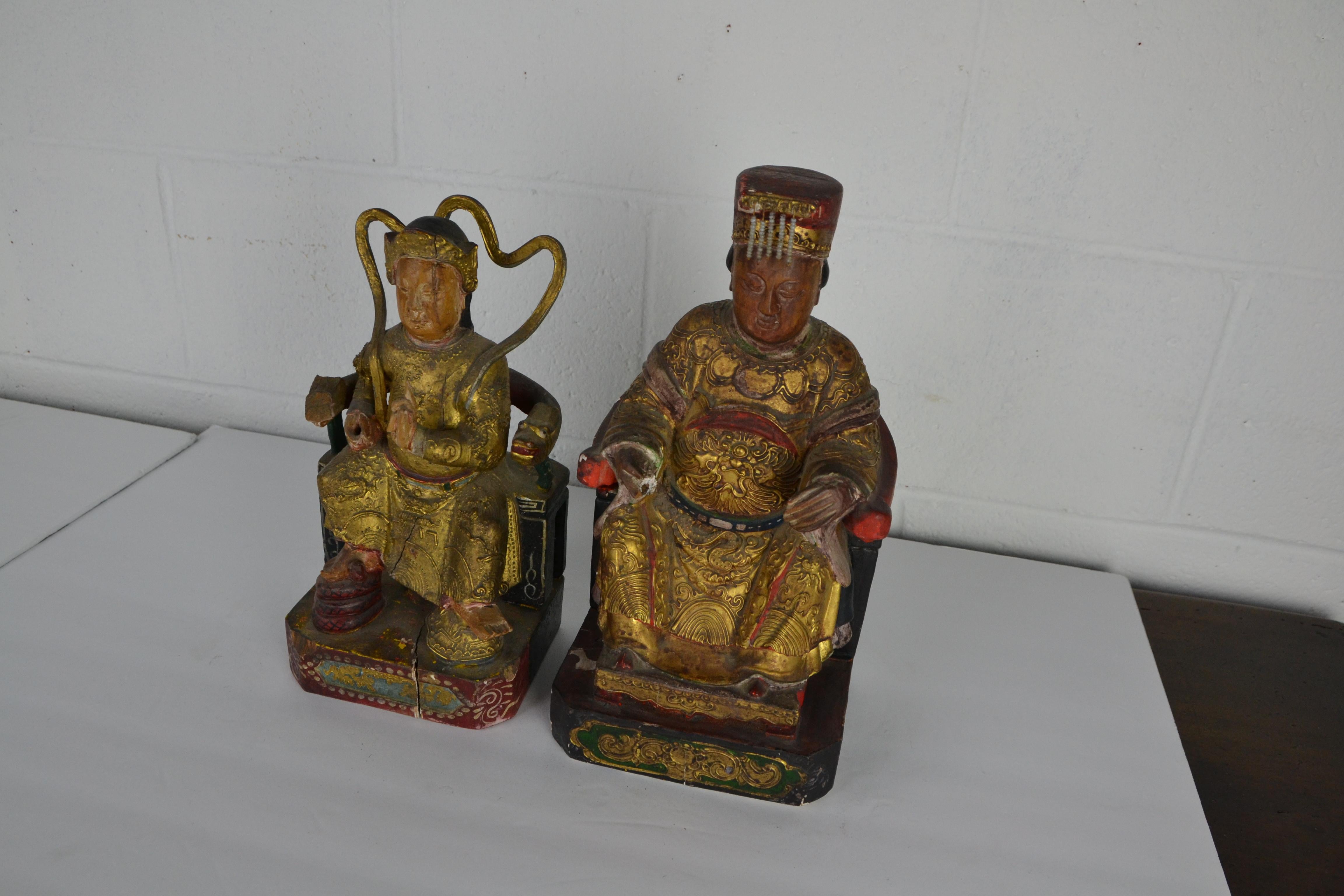 2 figurines chinoises assises en bois sculpté sans rapport. Les costumes sont bien détaillés, surtout sur la grande figure. Diverses pertes dans les détails et la finition. Perte de la main droite et de l'extrémité du bras droit de la chaise sur le