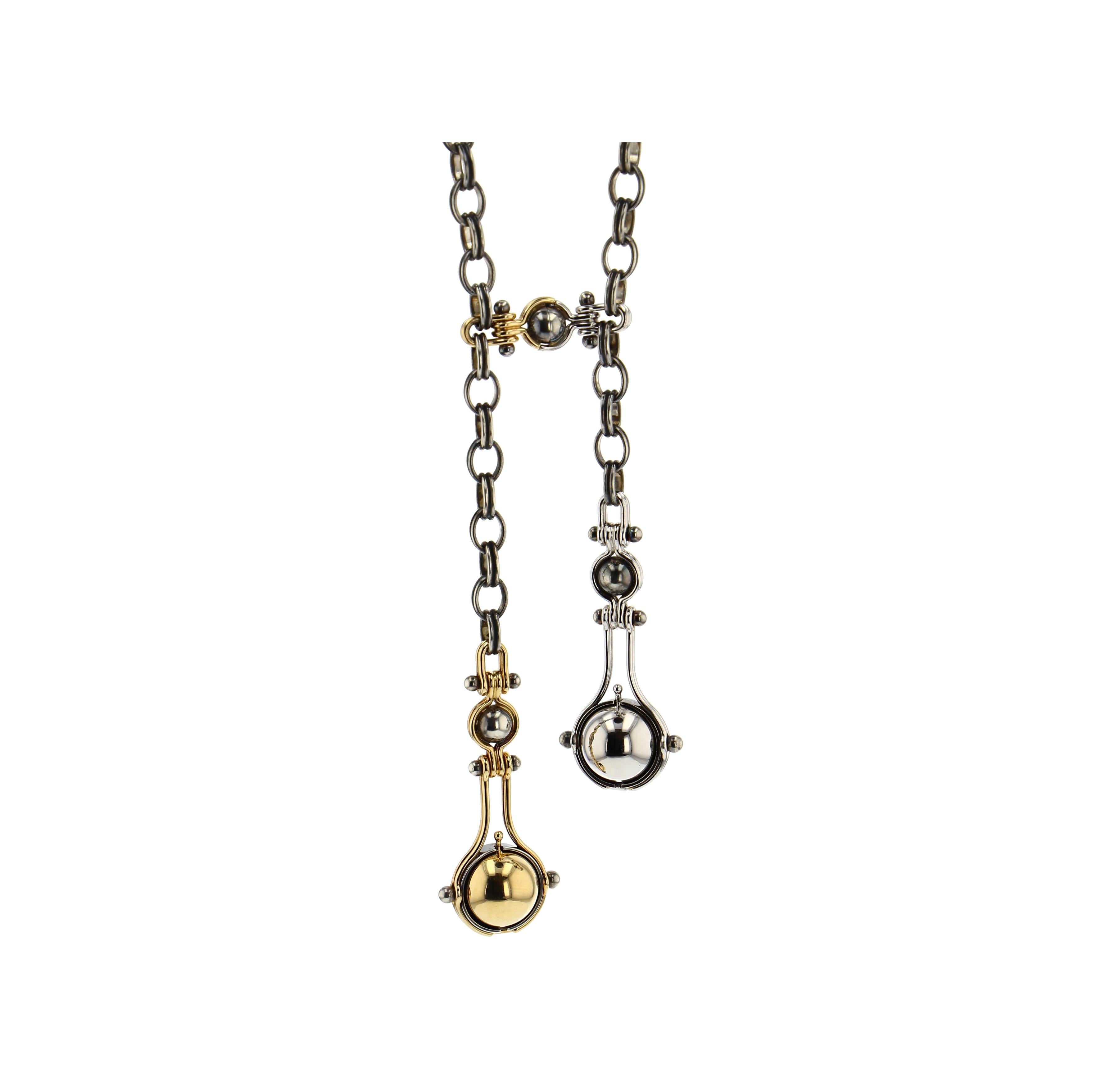 Tie necklace with a patinated silver chain. The two drops are madeof two yellow gold threads around a patinated silver globe supporting a mobile structure. It supports a rotating yellow gold sphere which reveals, on one side a white diamonds bead,