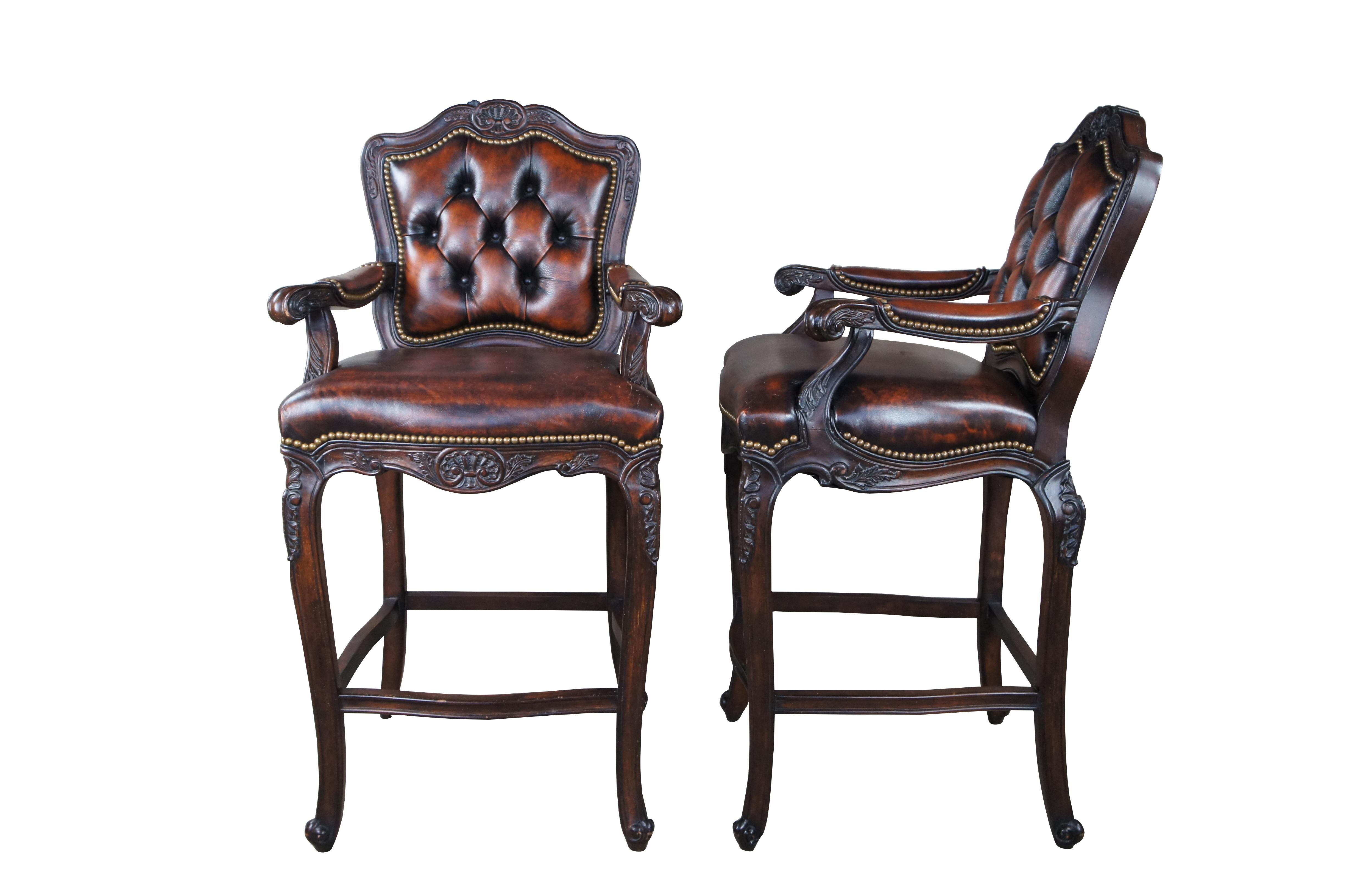 Pair of Hancock & Moore French Country / Louis XV style bar stools.  Features a carved and scalloped frame with brown leather seats and tufted back.  Accented by brass nail head trim over long cabriole legs with scrolled feet. MSRP