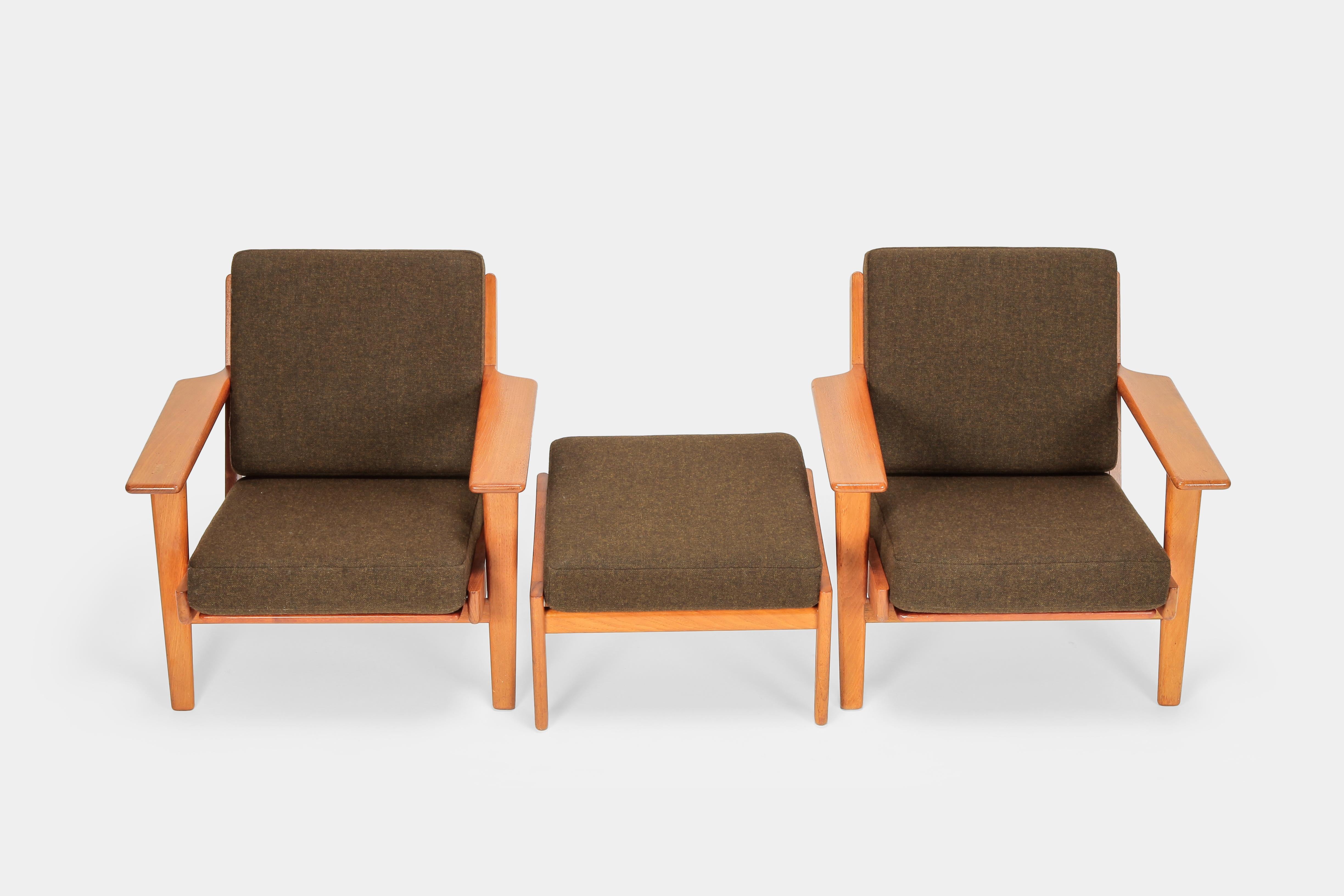 Two Hans Wegner GE290 chairs with one Ottoman made by Getama in Denmark in the 1950s. Solid teak frame, freshly upholstered and covered with new, woolen fabric. Warm and rustic Danish character, clear and solid lines with minute attention to detail