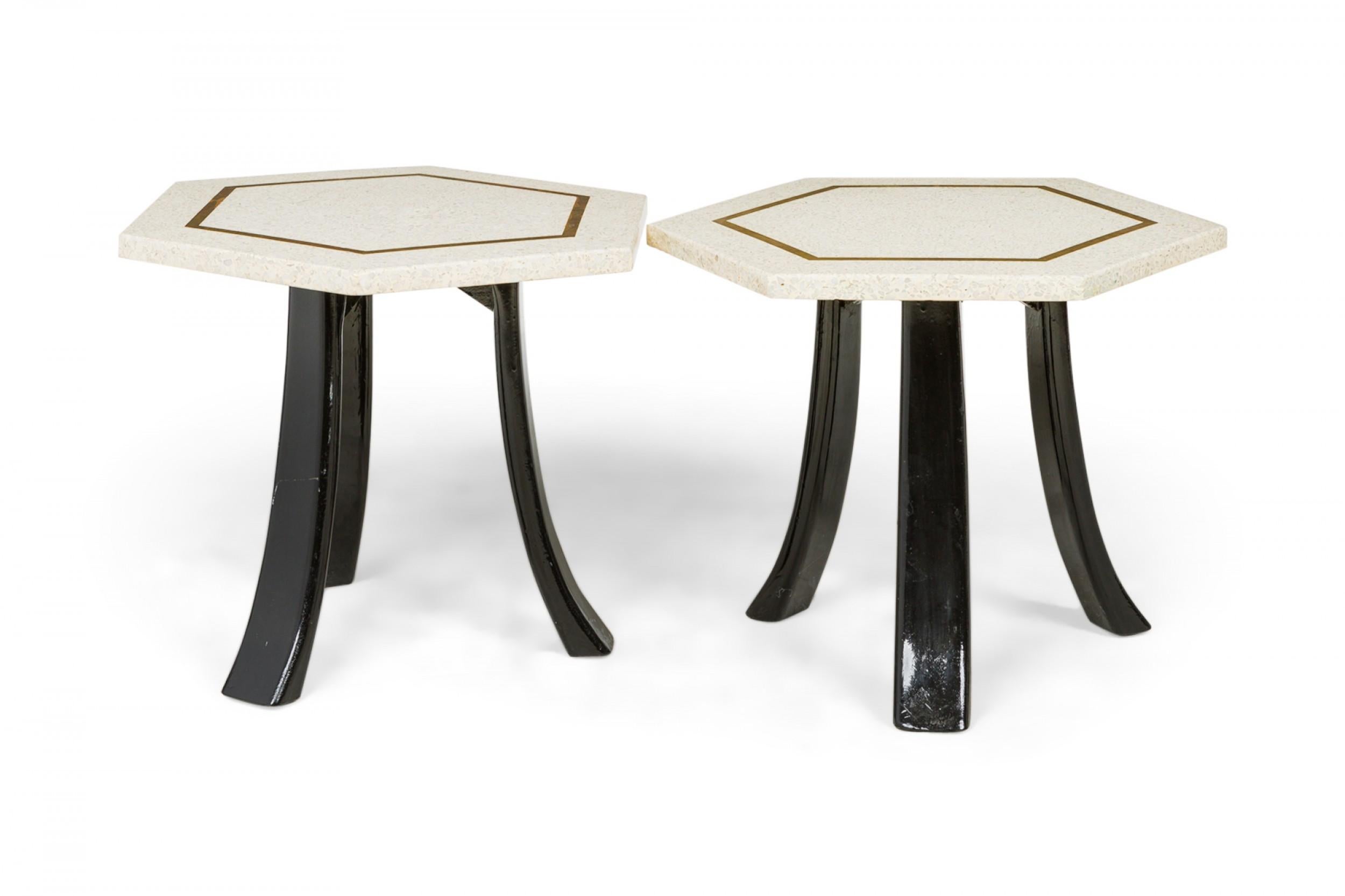 2 American mid-century end / side tables with hexagonal white terrazzo tops with a bronze inlaid hexagonal design supported on three curved black lacquered wooden legs. (Harvey Probber)(Priced Each).
   