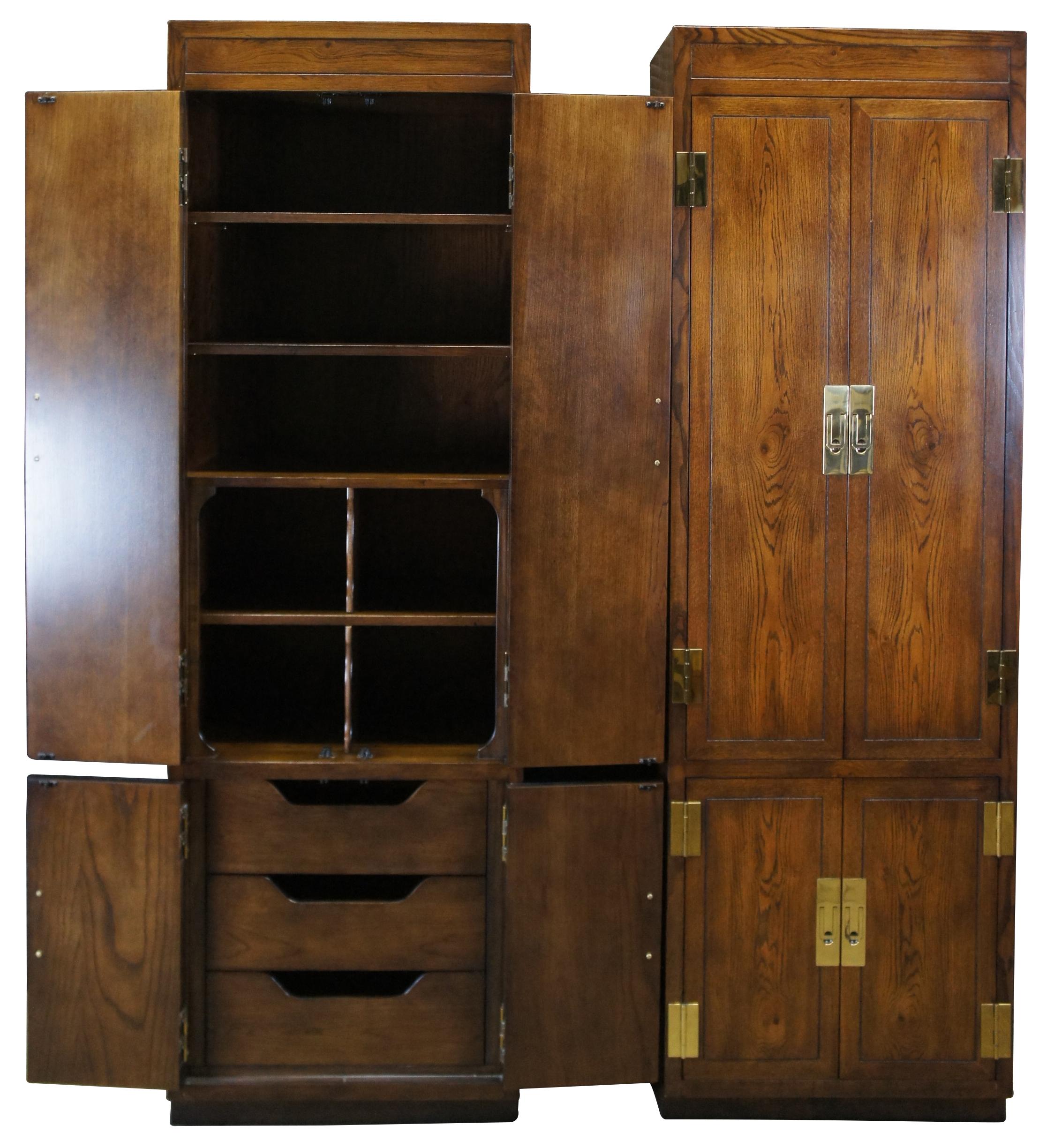 Two vintage Henredon scene I campaign style clothing armoires or wardrobe cabinets. Made of oak featuring upper shelves with four central cubbies and three lower drawers. Accented with modern brass hardware. Circa 1986s. 9100-05. 3162890. Measures: