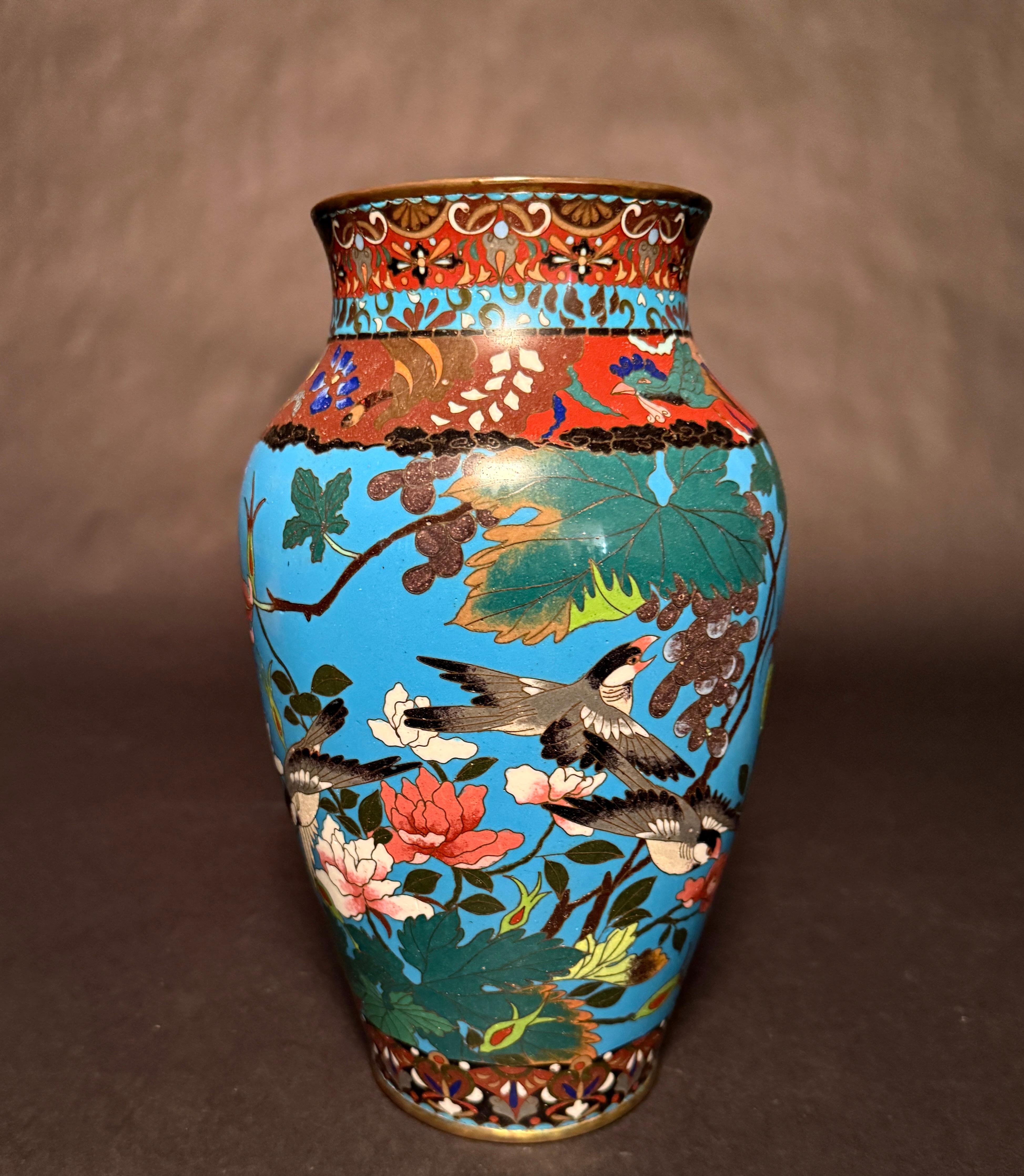 Near pair of late Meji period turquoise ground cloisonne vases with birds and foliage motif. Bright colors with good enameling, cranes, butterflies and sparrow birds surrounded by florals and vines. Top border with geometrics and additional florals.