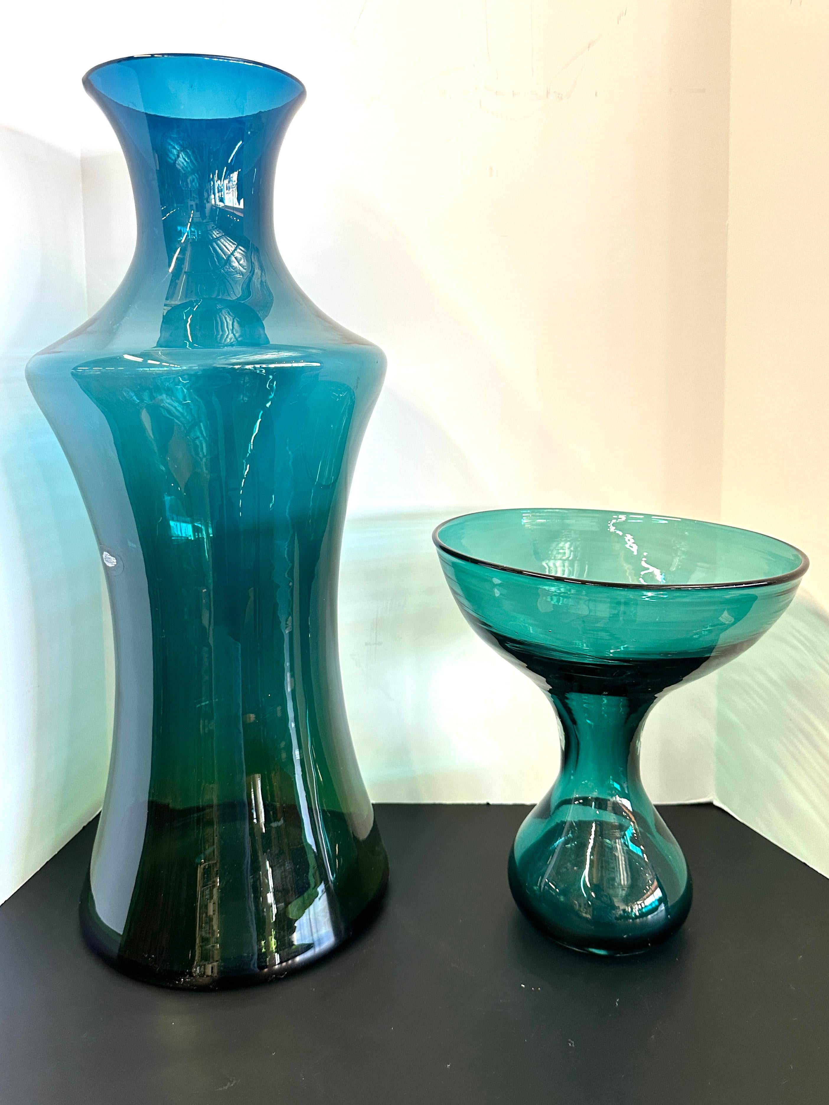 Estas piezas de cristal nos atrajeron inmediatamente por su hermoso color y su gran forma. Estas dos bellezas llevan la marca Blenko. Una está firmada Blenko en la base y la otra tiene una etiqueta de Blenko. 
Ambos están en buen estado, con