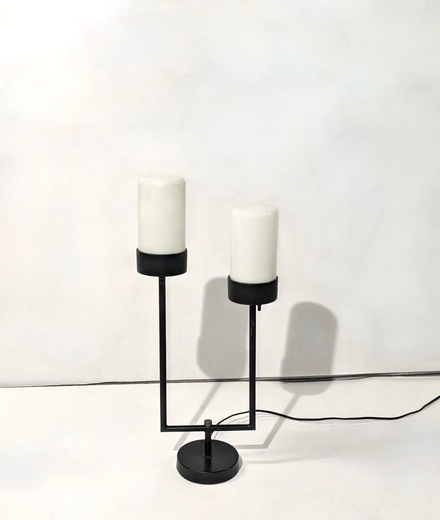 Table lamp by Robert Bulmore in black enameled iron, brass hardware, and two cylindrical shades of white, opaque glass. Each light has its own on/off switch. 