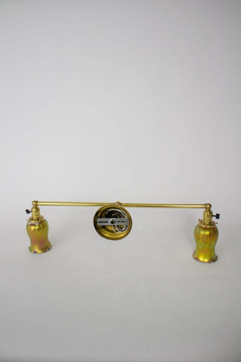 Two light wall sconce. Irridescent american made art glass shades. Polished Brass.

Material: Brass, Art glass
Style: Transitional, Traditional
Place of Origin: United States
Period made: Early 20th century
Dimensions: 28 × 9 × 12