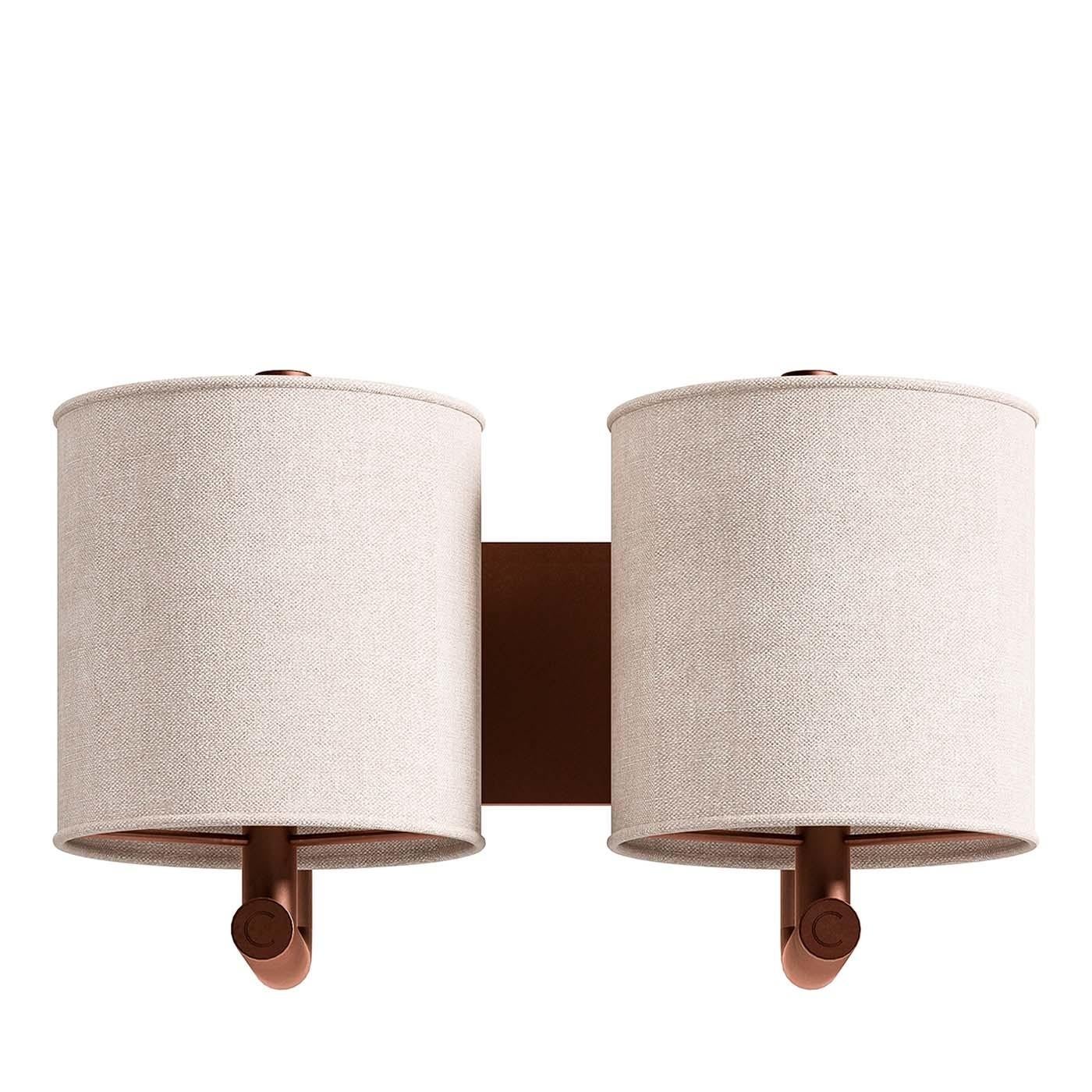 Merging traditional lines with a vintage decorative touch, this wall sconce is a versatile illumination that will fit in a traditional and midcentury decor. Two curved arms extend from a rectangular wall plate in metal with a brushed-copper finish,