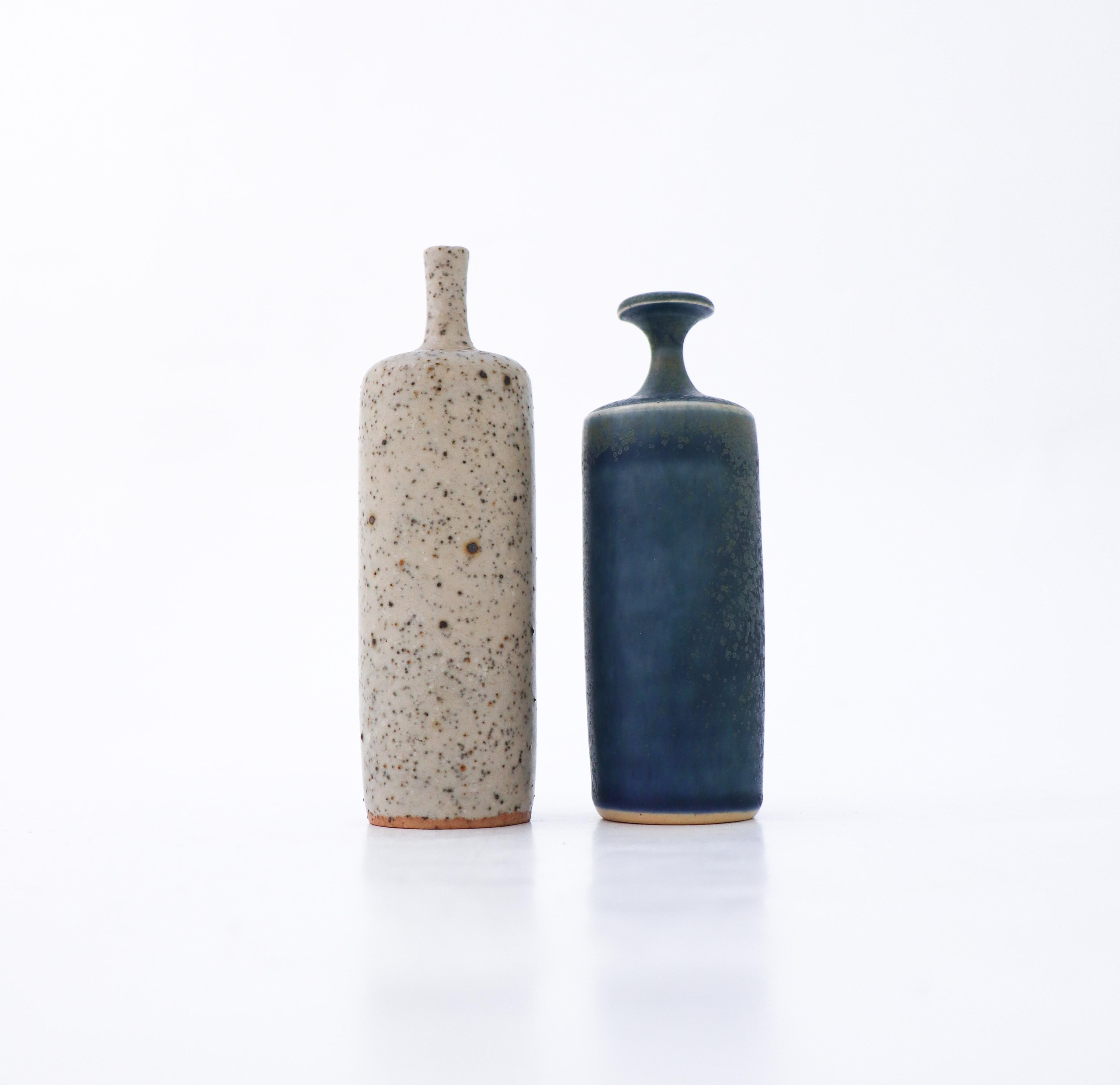 A pair of lovely vases designed by Rolf Palm at his workshop in Mölle outside Höganäs in Sweden, one with a lightgray color with a raw surface and the other one with a blue almost crystalline glaze. The vases are 12 and 11 cm (4.8