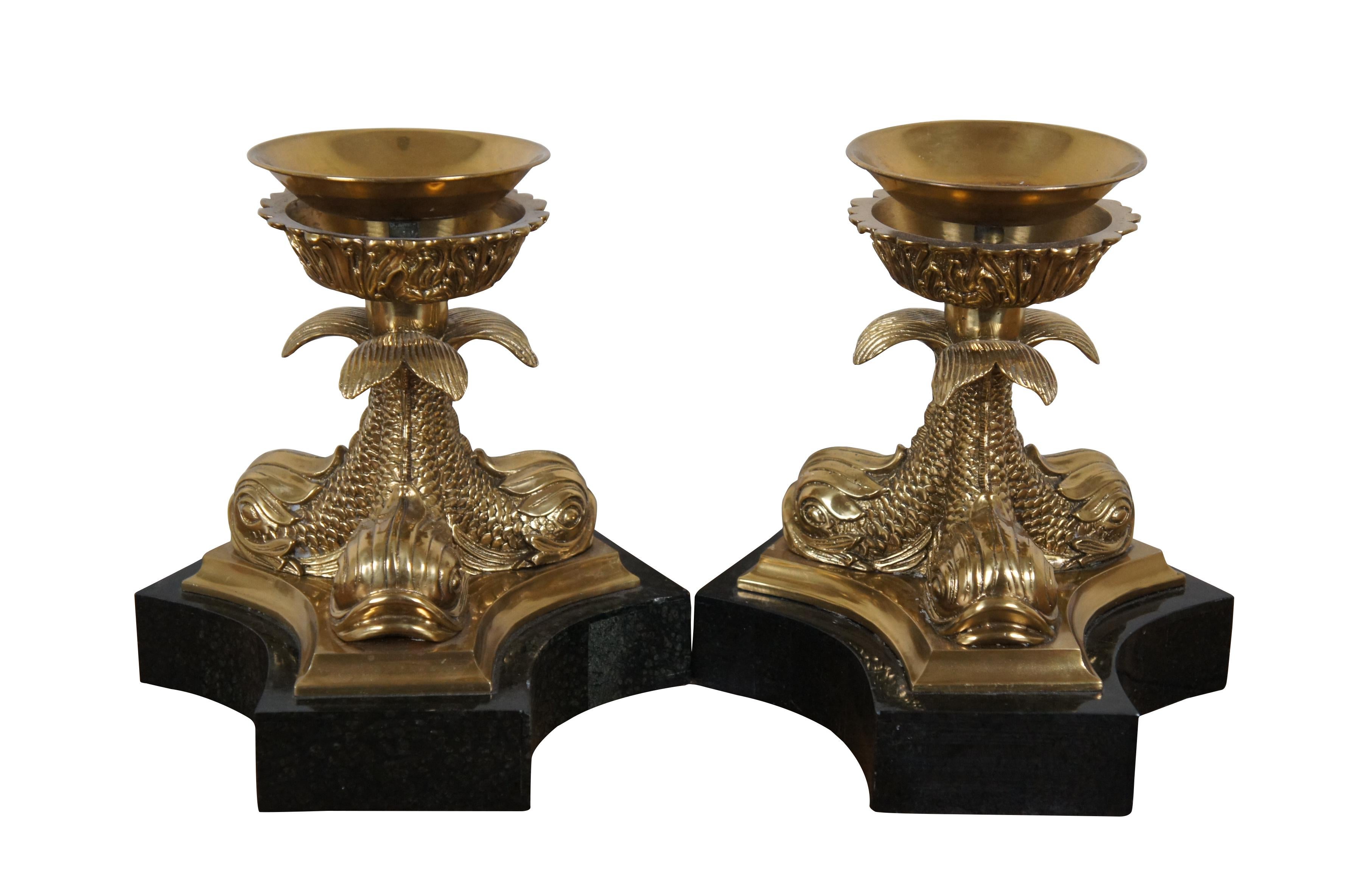 Pair of late 20th century Maitland-Smith hurricane candlestick candleholders featuring a trio of bright brass delphins / dolphins / fish supporting acanthus leaf trimmed candle cups with adjustable drip pans, on tripod shaped, black marble clad