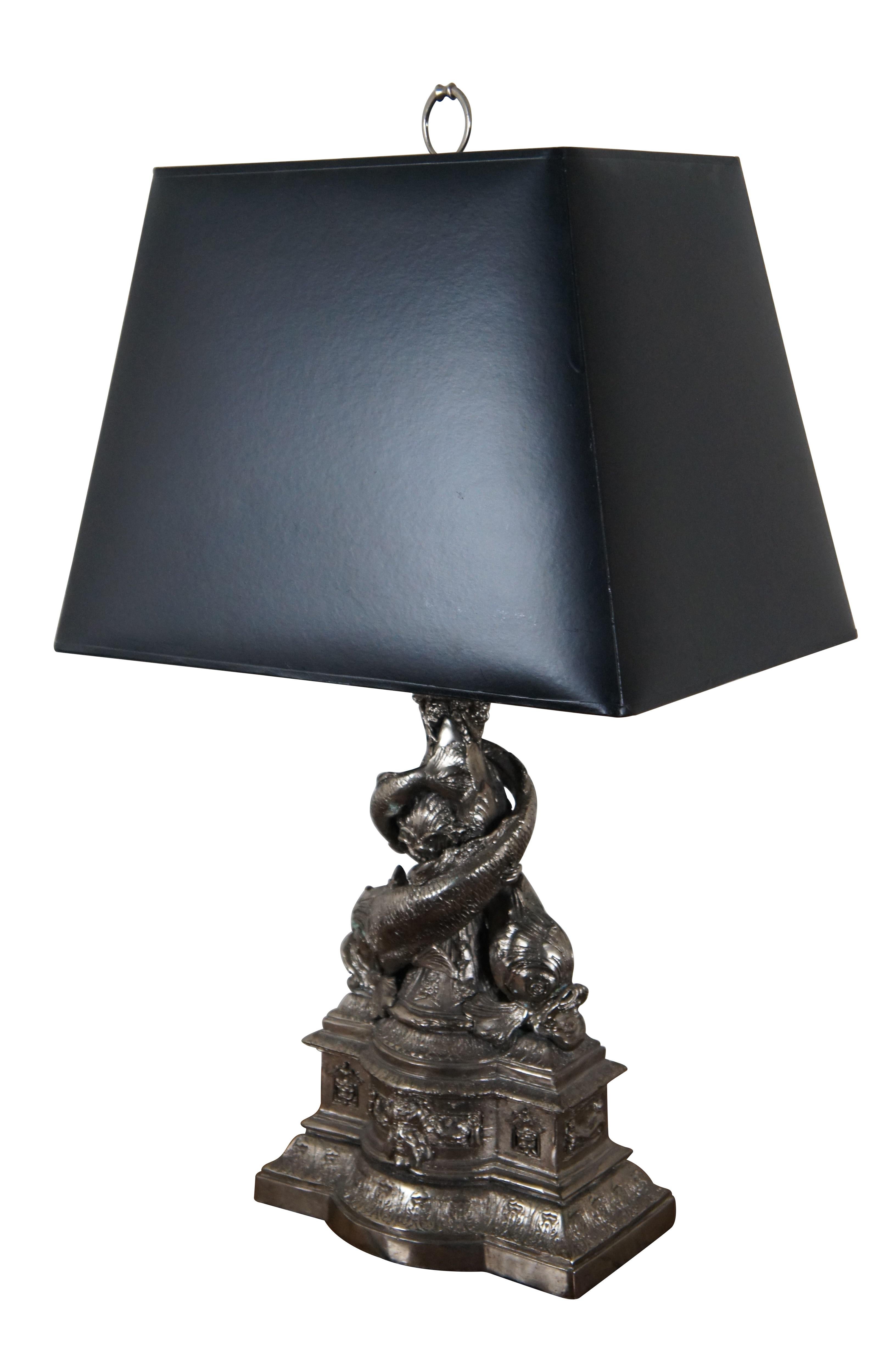 Rare vintage Maitland Smith table lamps, made of heavy cast metal with a bright silver finish, showing a Neoclassical style pedestal like the base of a fountain accented with the face of a bearded man with a cadeuceus at each corner, below a vase