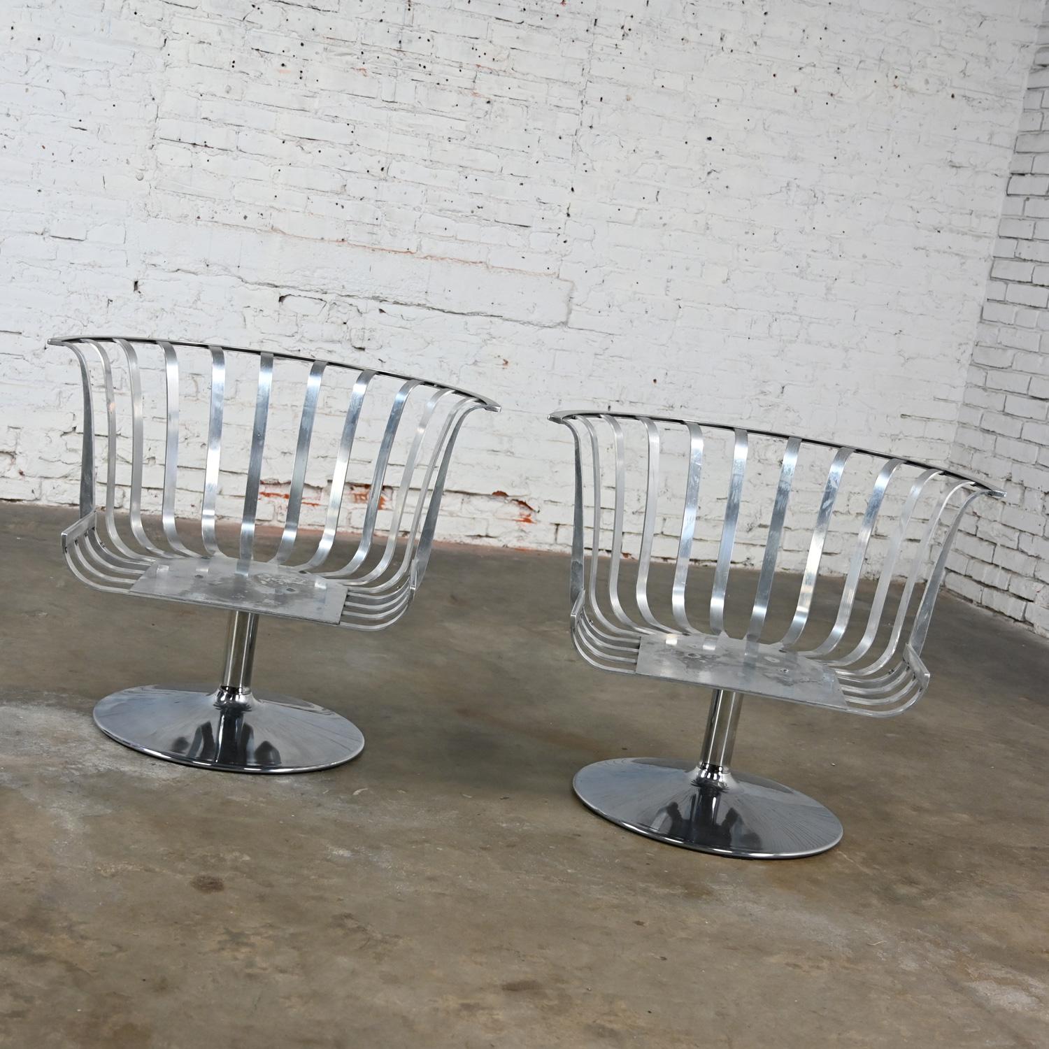 Handsome vintage MCM (Mid-Century Modern) polished aluminum and chrome tulip base barrel swivel lounge chairs by Russell Woodard, a pair. This piece has been attributed based upon archived research including online sources, vintage documentation and
