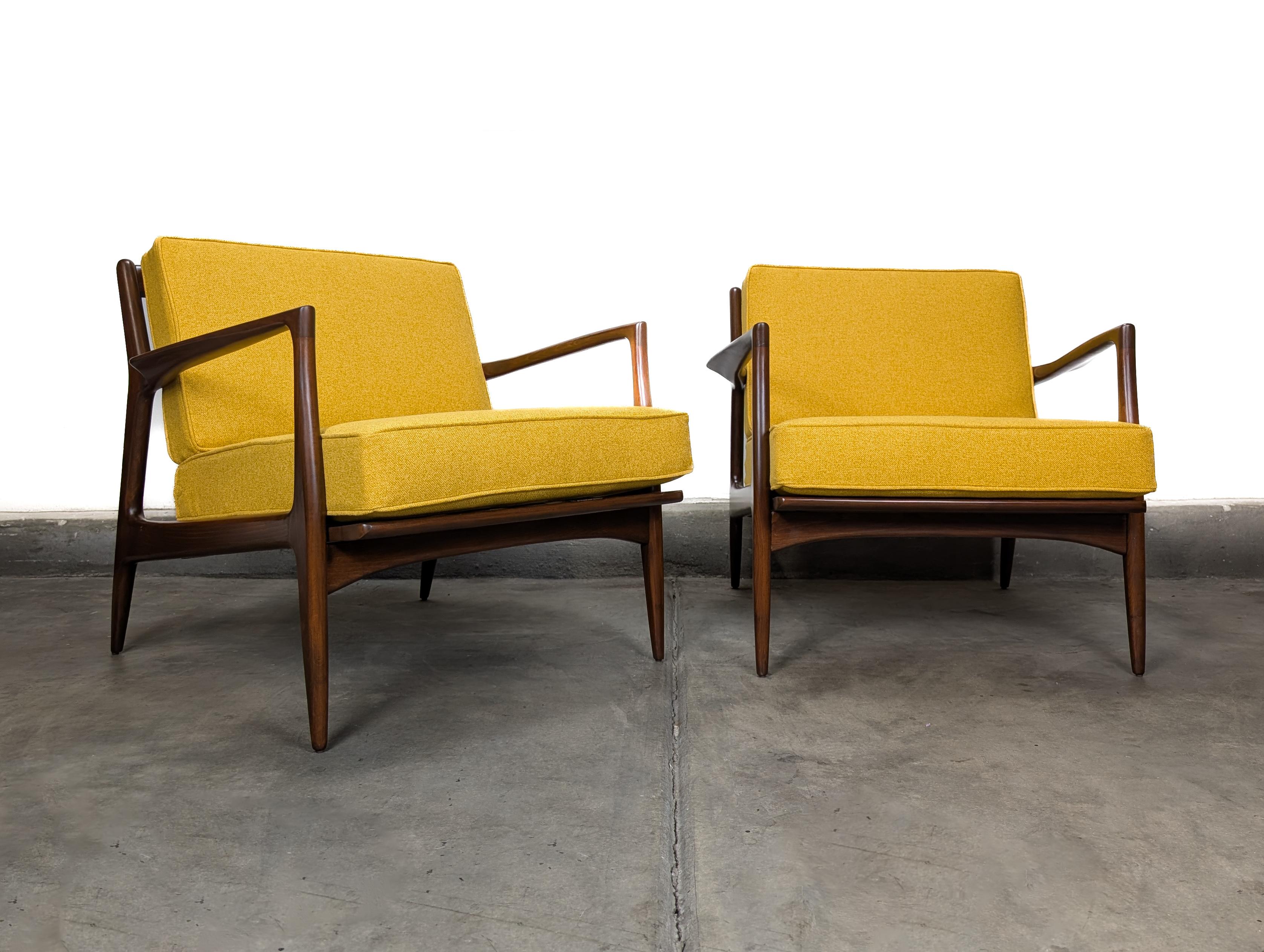 This set of two Mid-Century Modern “Blade Arm” lounge chairs by Ib Kofod-Larsen for Selig, Denmark (c.1960s) represents the finest in Danish design and craftsmanship. Fully and meticulously restored, these iconic Scandinavian lounge chairs feature