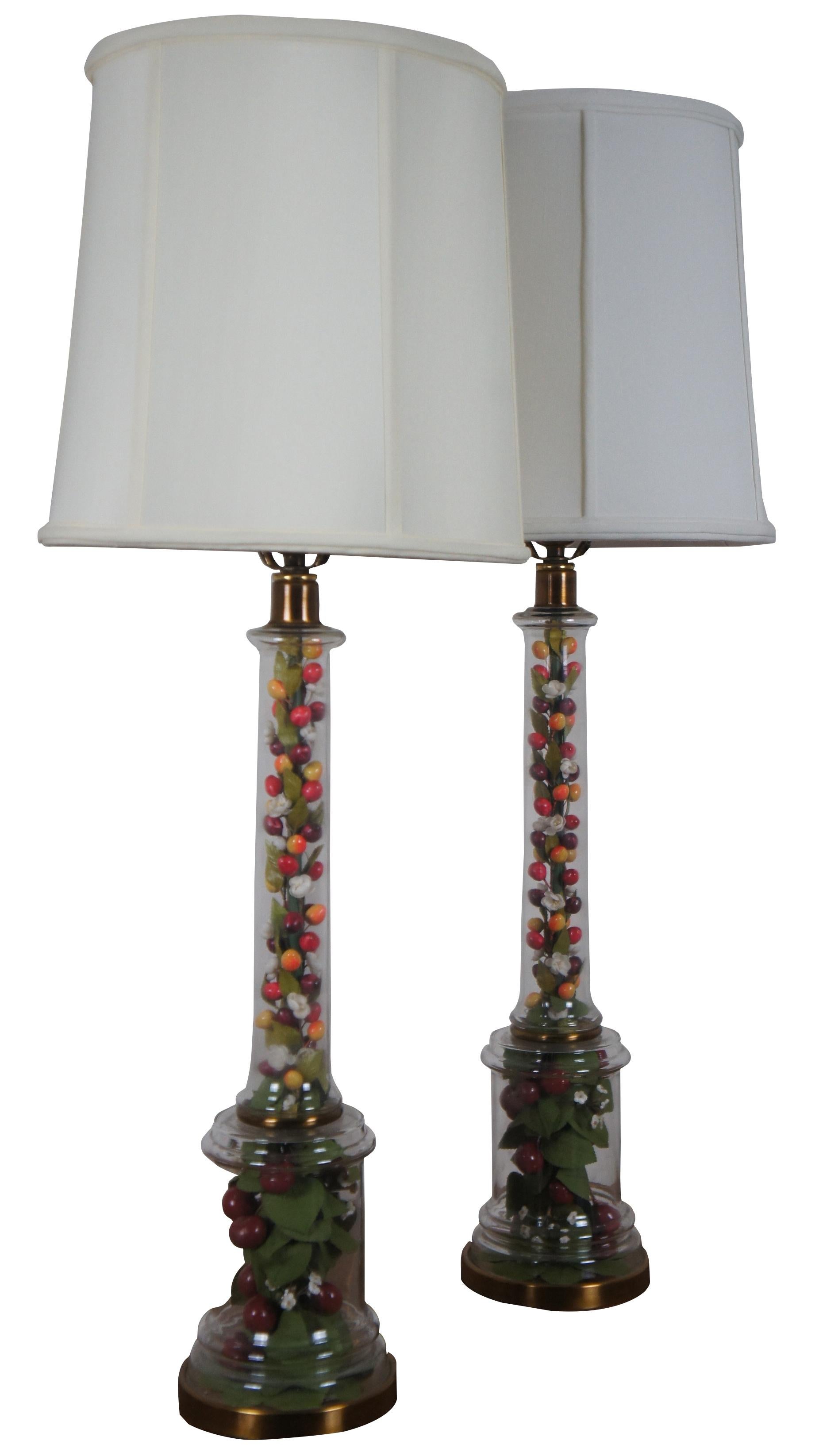 Mid century Frederick Cooper brass and glass table lamp pair featuring a clear glass column display filled with a festive arrangement of artificial flowers, leaves, fruits and berries.

Measures: 5.75” x 34.5” / Shade - 12.25” x 12.25” (Diameter x