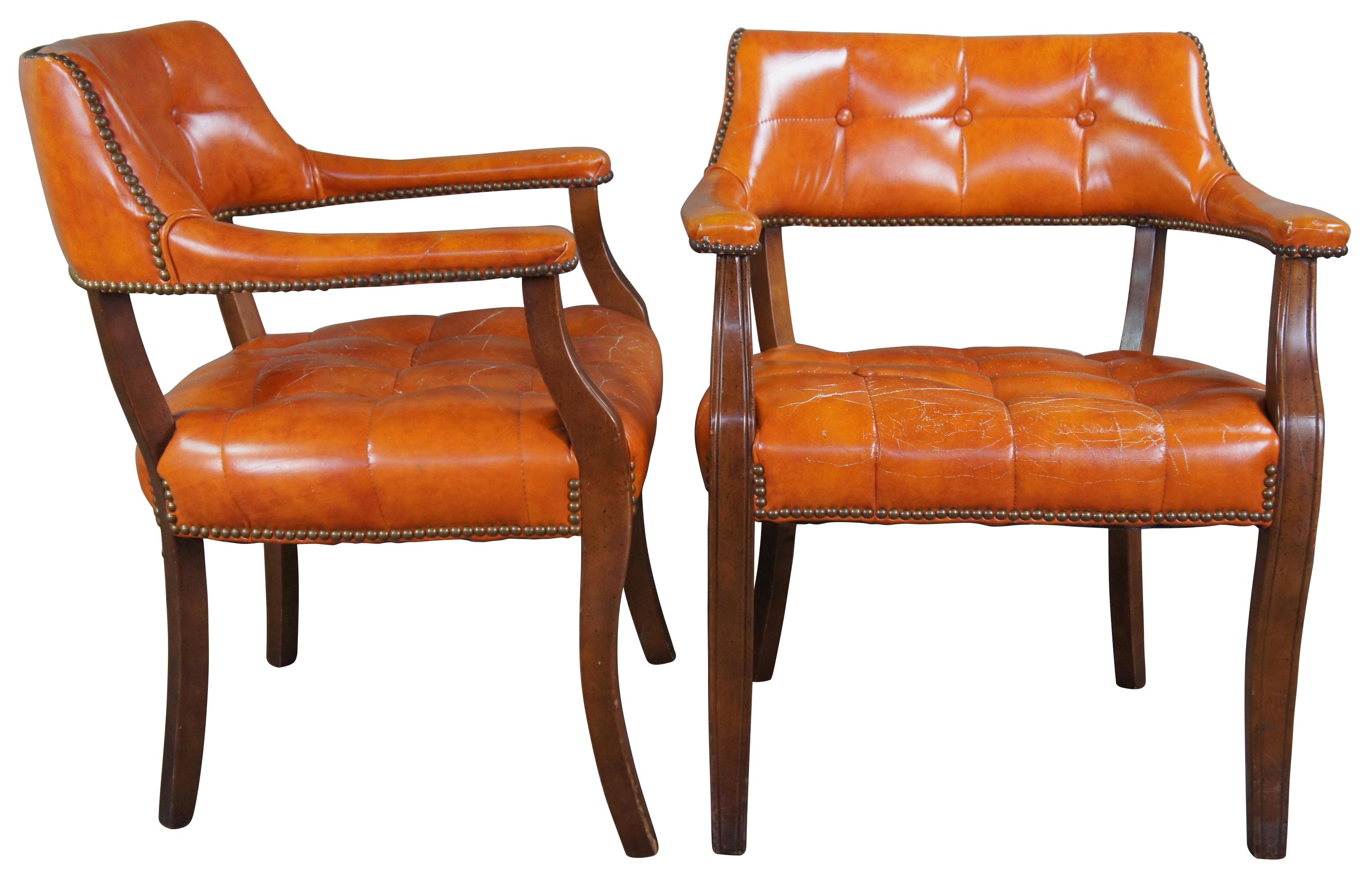 Pair of mid century orange vinyl tufted barrek back chairs. Features a a naturally distressed frame and brass nailhead trim.
 