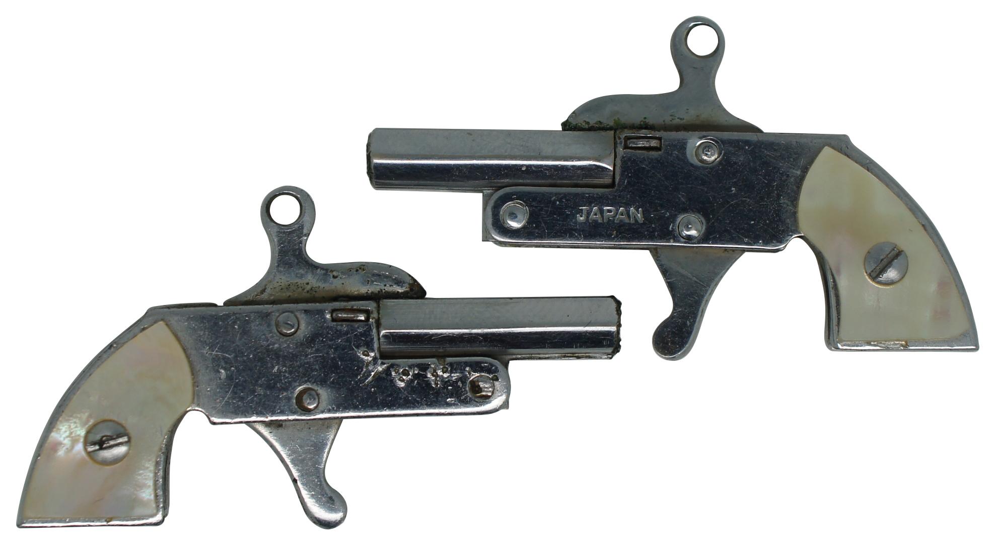 Vintage miniature pin fire cap gun pair with mother of pearl on the handles, made in Japan with small ring on top of the barrel for use as a key chain or watch fob. Includes set of 2mm blank cartridges and ram rod.
 