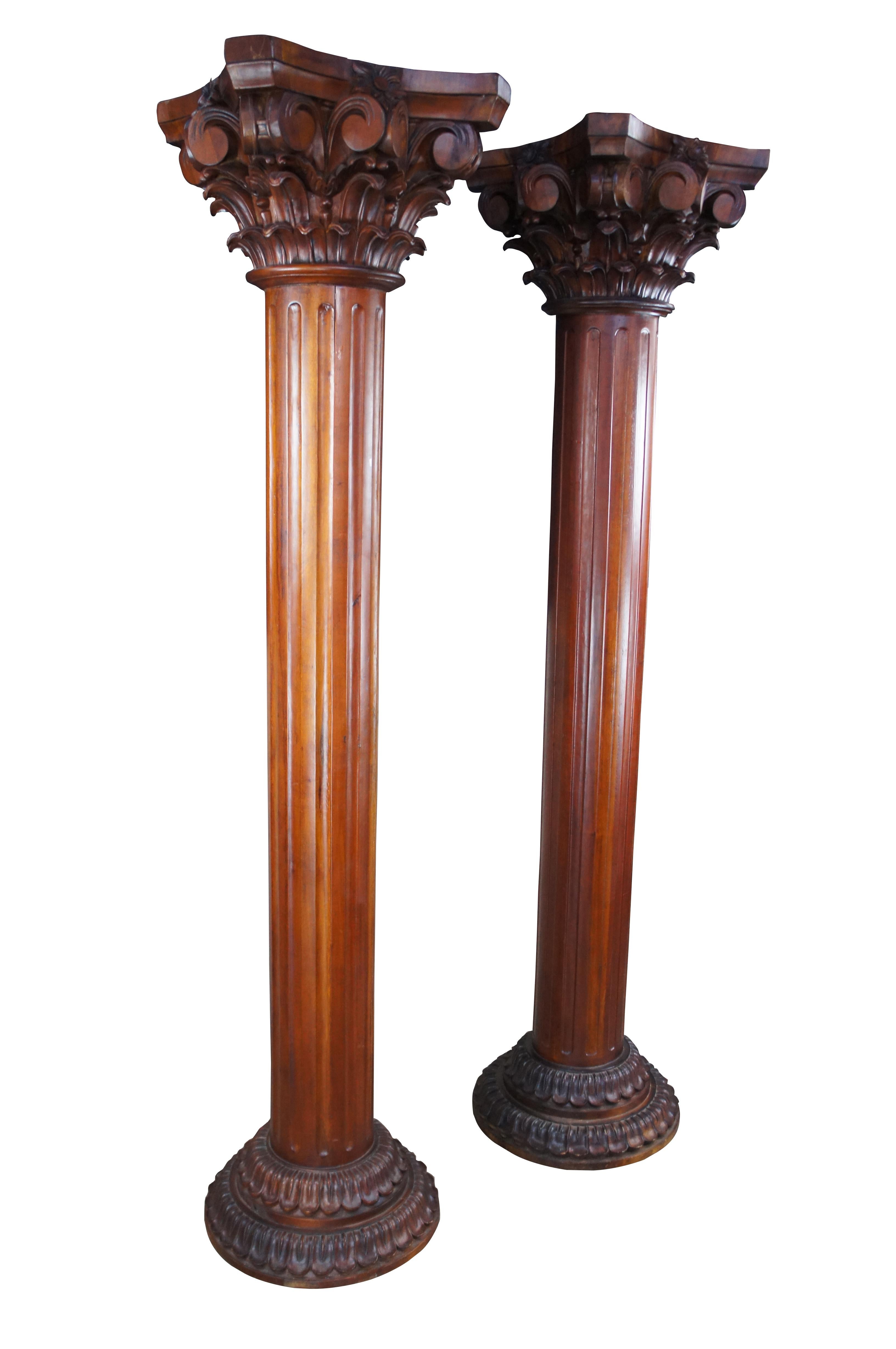 A massive pair of late 20th century mahogany Grecian style columns. Each showcases a large carved capital over a fluted center and tiered foliate base. Great for ornamental use or display. The two columns could be used for display or functioning as