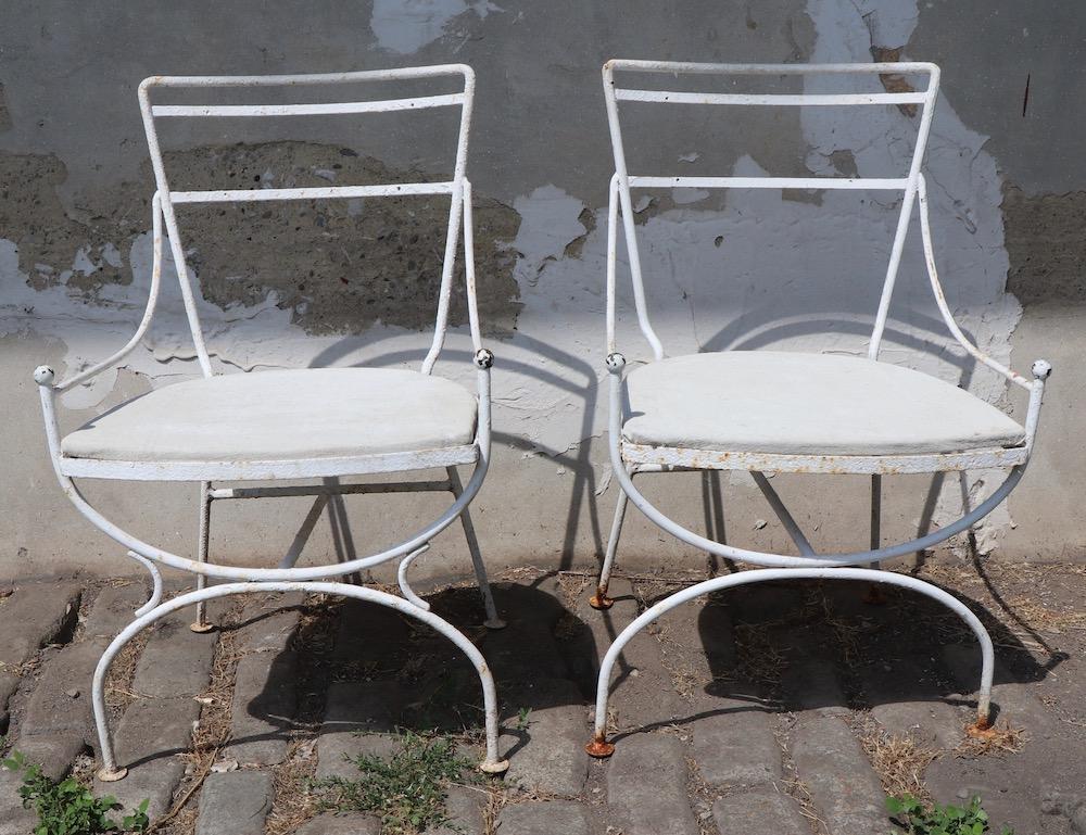 Stylish and chic garden or patio lounge chairs each having wrought iron frames with decorative brass ball finial handles and upholstered seats. Both chairs are currently in older white paint finish, both having several coats of paint, seats show