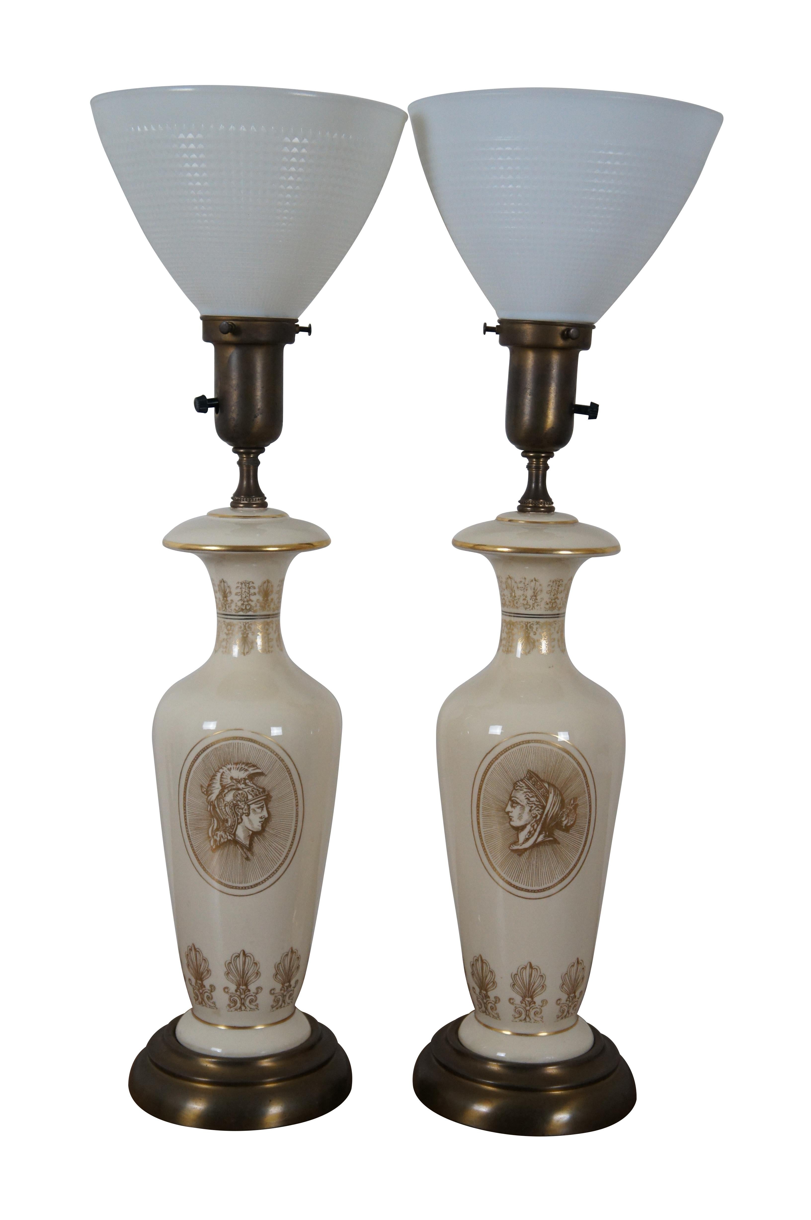 Pair of vintage off-white porcelain mantel urn table lamps with brass bases, stenciled with neoclassical motifs including the heads of a Roman / Greek soldier and noblewoman. Topped with waffle-textured milk glass torchiere up light shades and