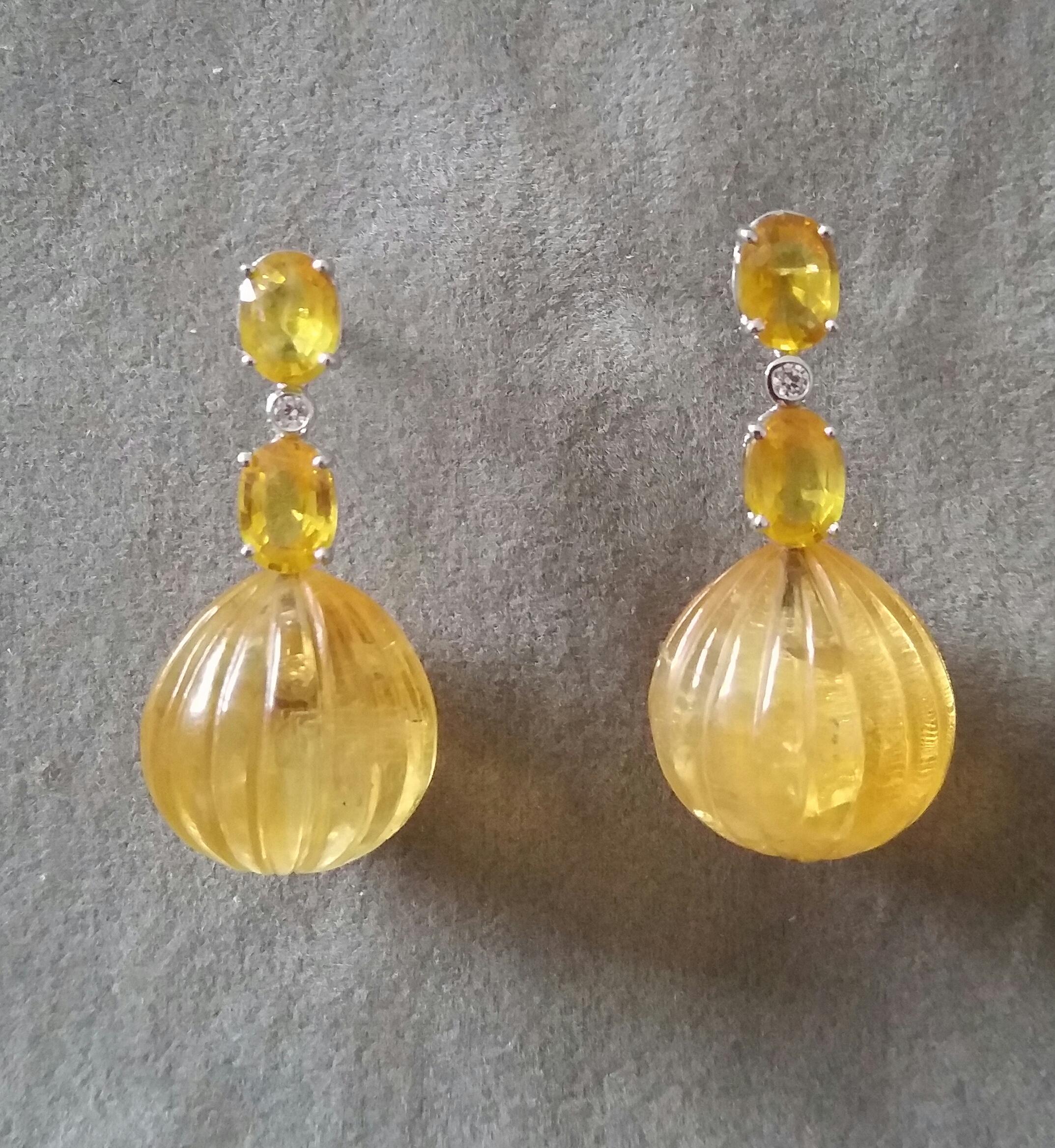 Elegant and completely handmade Earrings consisting of an upper part of 2 faceted oval shape  Yellow Sapphires of 5 mm x 7 mm set together in 14 Kt white gold with a  small diamond in the middle, at the bottom 2  Carved Round Citrine Drops measuring