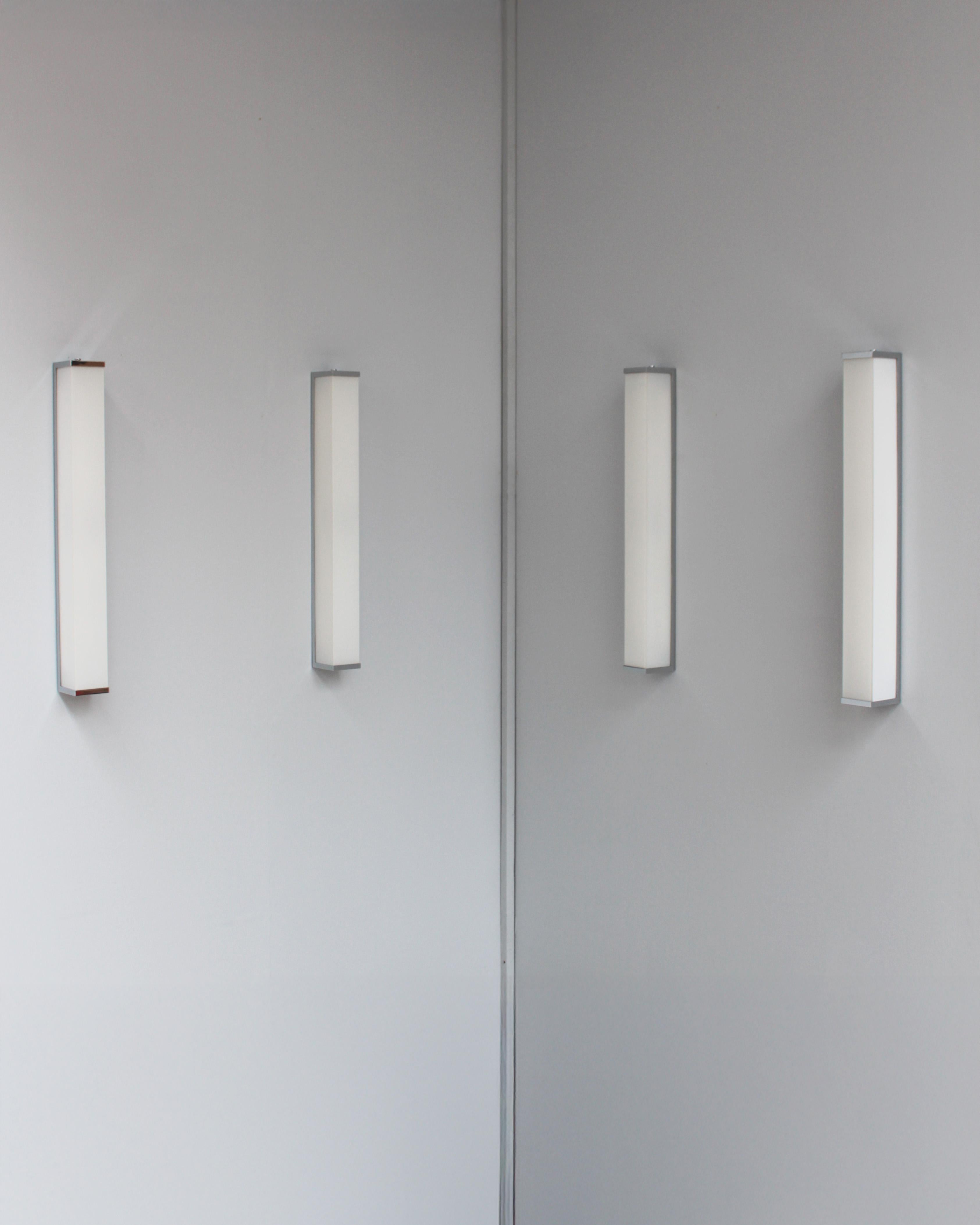 Due coppie di raffinate lampade da parete rettangolari in stile Art Déco francese con vetro smaltato bianco montate su una cornice in nichel con bordo cromato.
    
Il prezzo si intende per coppia