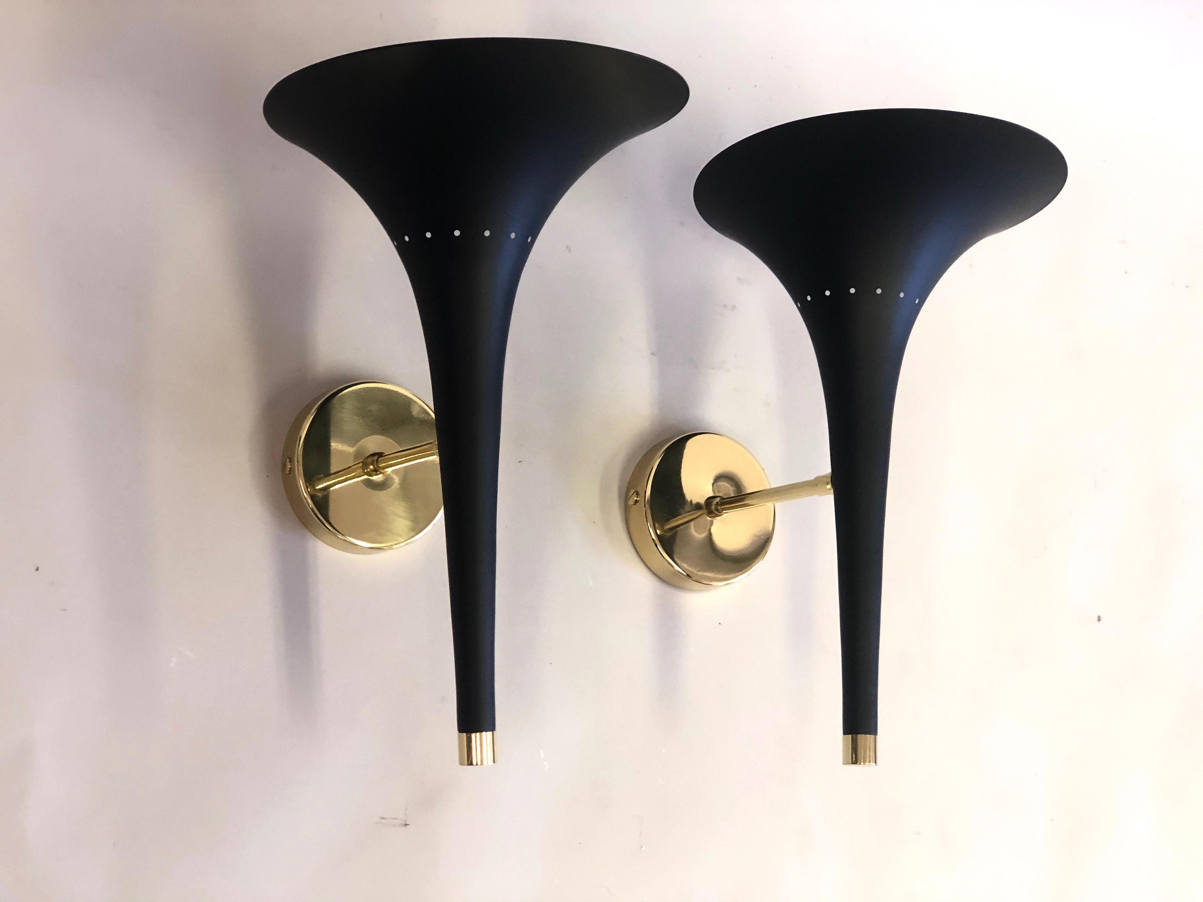 2 Pairs of Italian Mid-Century Modern black enameled metal and brass wall lights attributed to Stilnovo. The black enameled metal reflector is delicately tapered ending in a flared oval form from which light is emitted. 1 Candelabra socket.
The