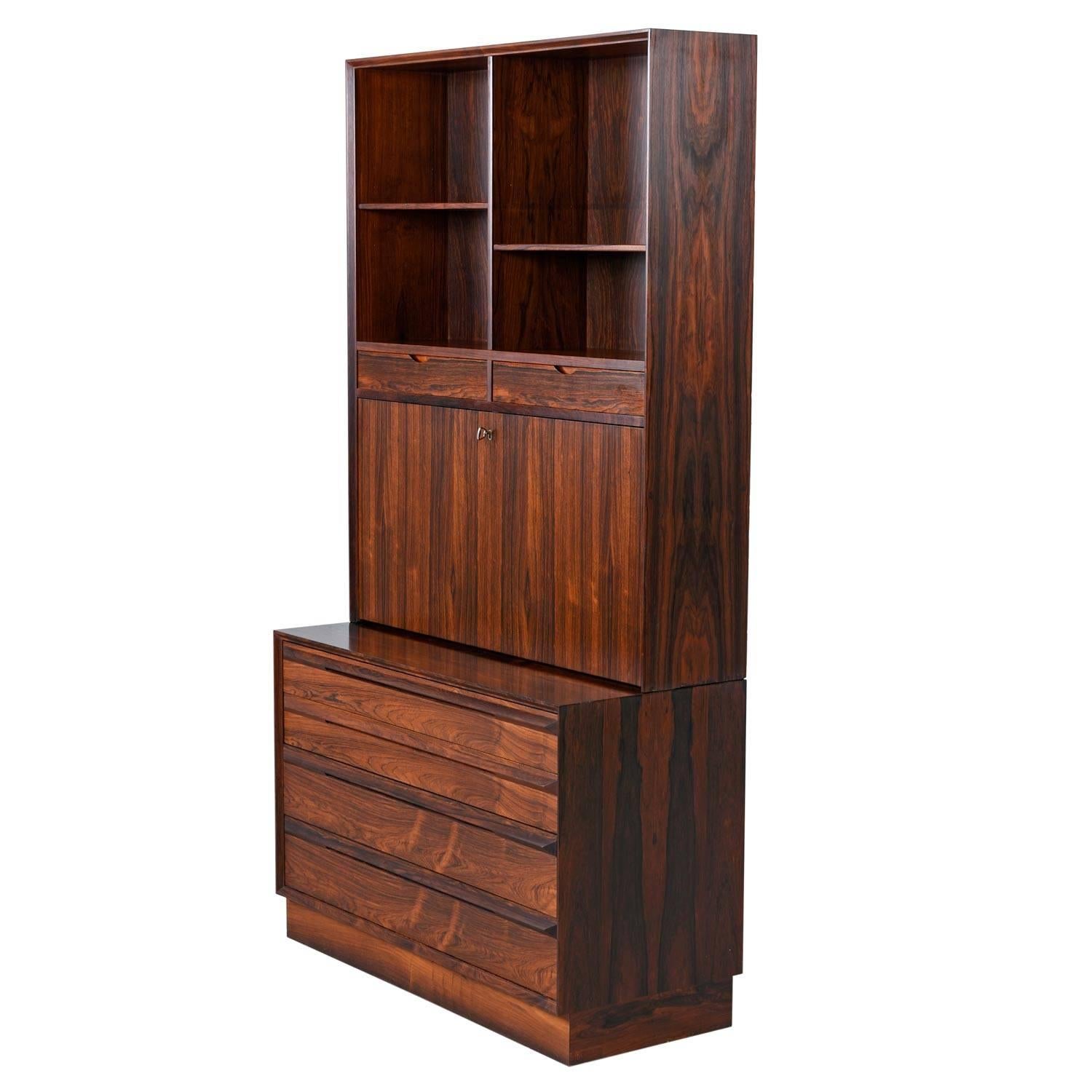 Exquisite Danish made two piece bookcase chest of drawers with secretary desk. The piece packs a wallop with storage capability. Store books and collectibles on the upper bookcase while serving drinks from the private, glass shelf storage bar.