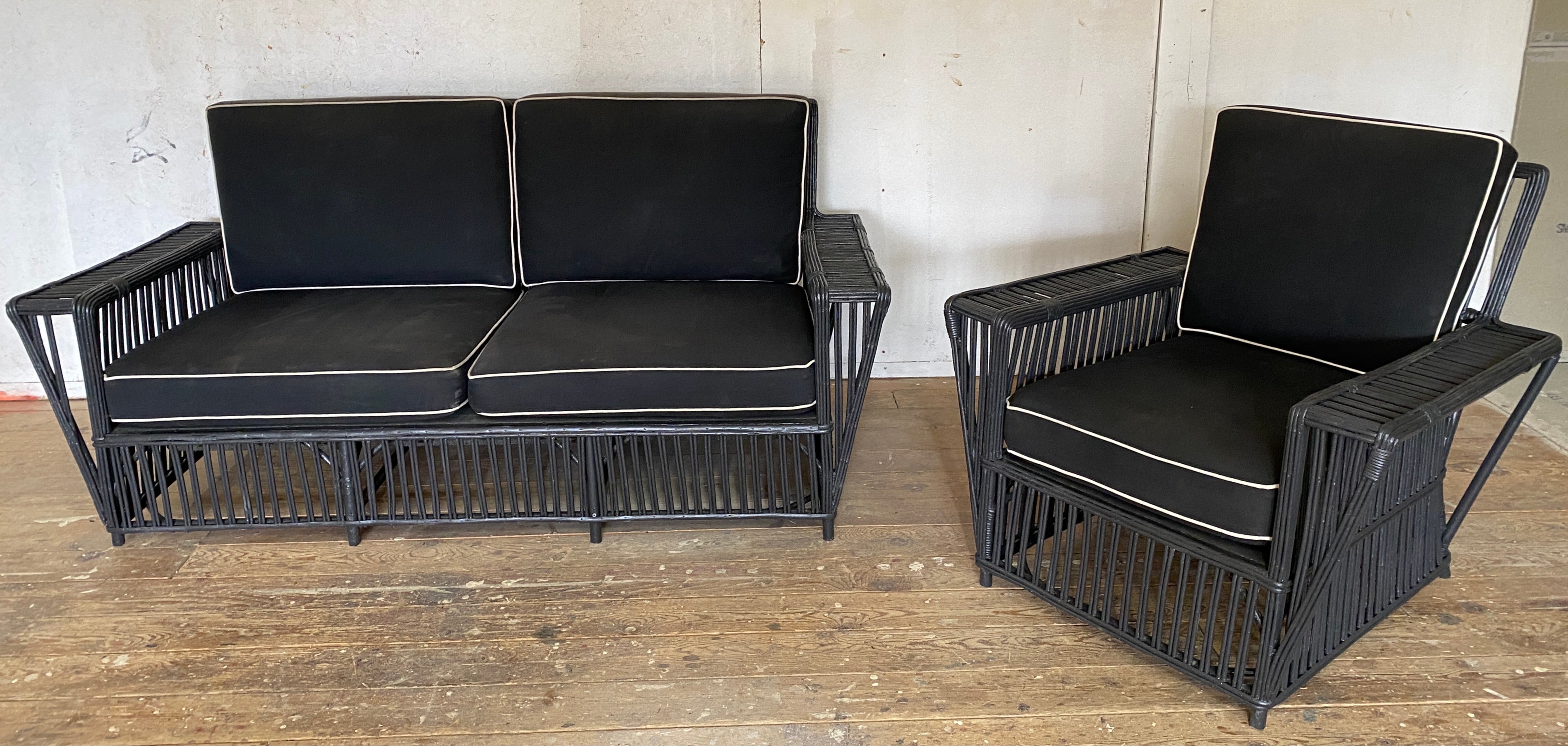 Stylish 1940's Stick Wicker / split reed sofa and armchair, deep-seated, angular with wide flat arms giving the sofa and chair that graceful elegant look. The rattan settee and arm chair are newly re-painted in a soft black paint. Cushions are