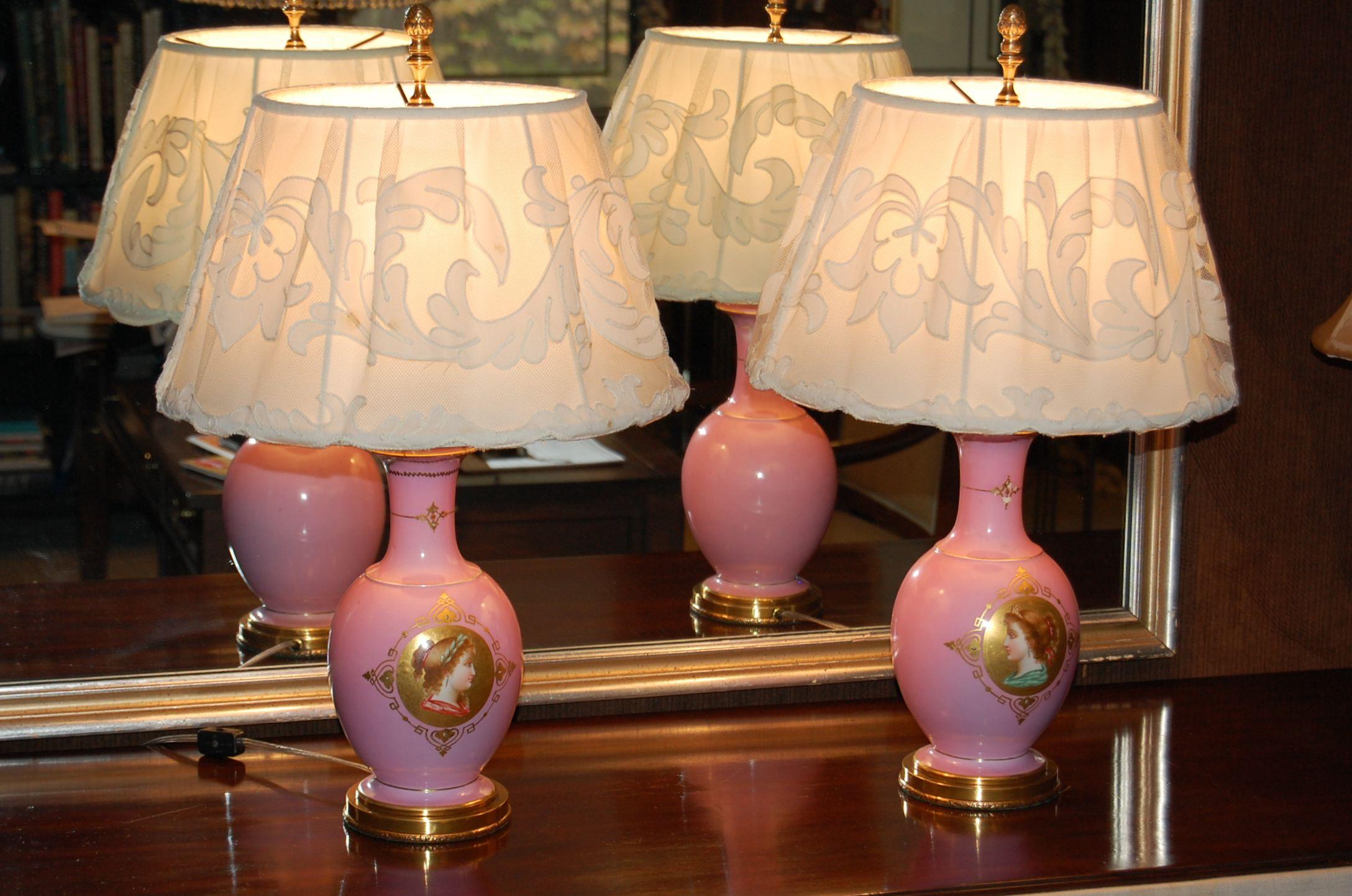 Pair of porcelain lamps just rewired with custom hand made cotton embroidered lampshades. The lamps each have a center medallion featuring a female bust hand painted on the front side. Mounted on brass bases. The shades were hand made in the 1980's