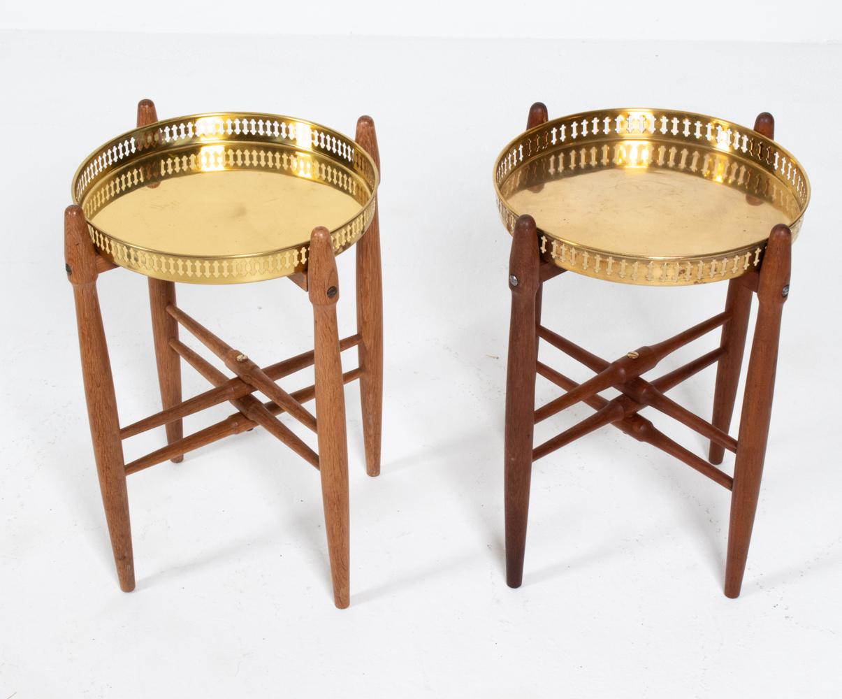 A fabulous matched pair of Danish mid-century side tables, one in lighter oak wood, one in slightly darker teak, both with pierced galleried brass tray tops, designed by Poul Hundevad. Classic Scandinavian modern design, reflected in the tapered,