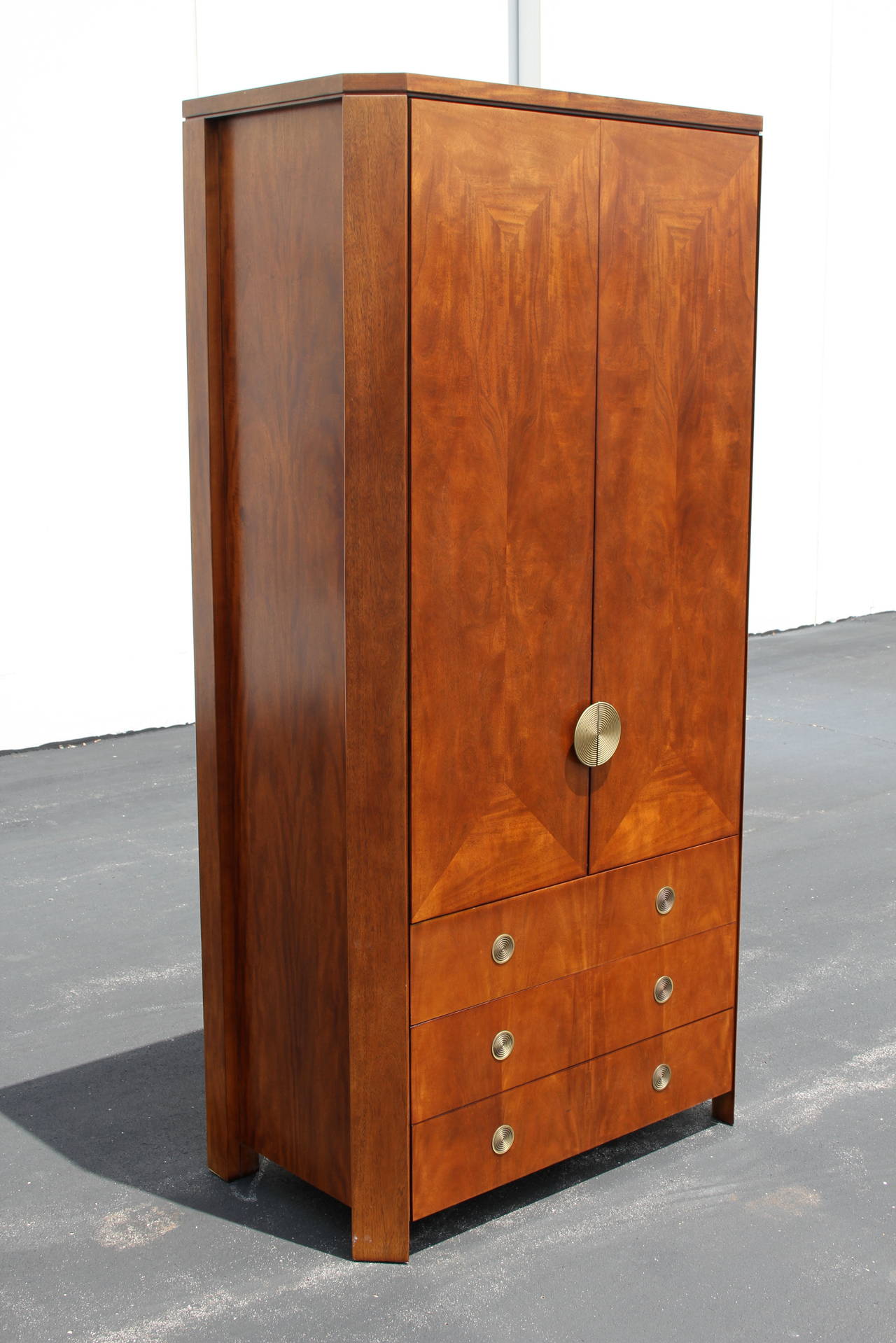 Rare tall skyscraper form Armoire designed by Charles Pfister for Baker, with cabinet doors above three drawers, all with concentric Art Deco styling brass circular hardware, circa 1989. Primavera mahogany in a medium brown tone. Better photos