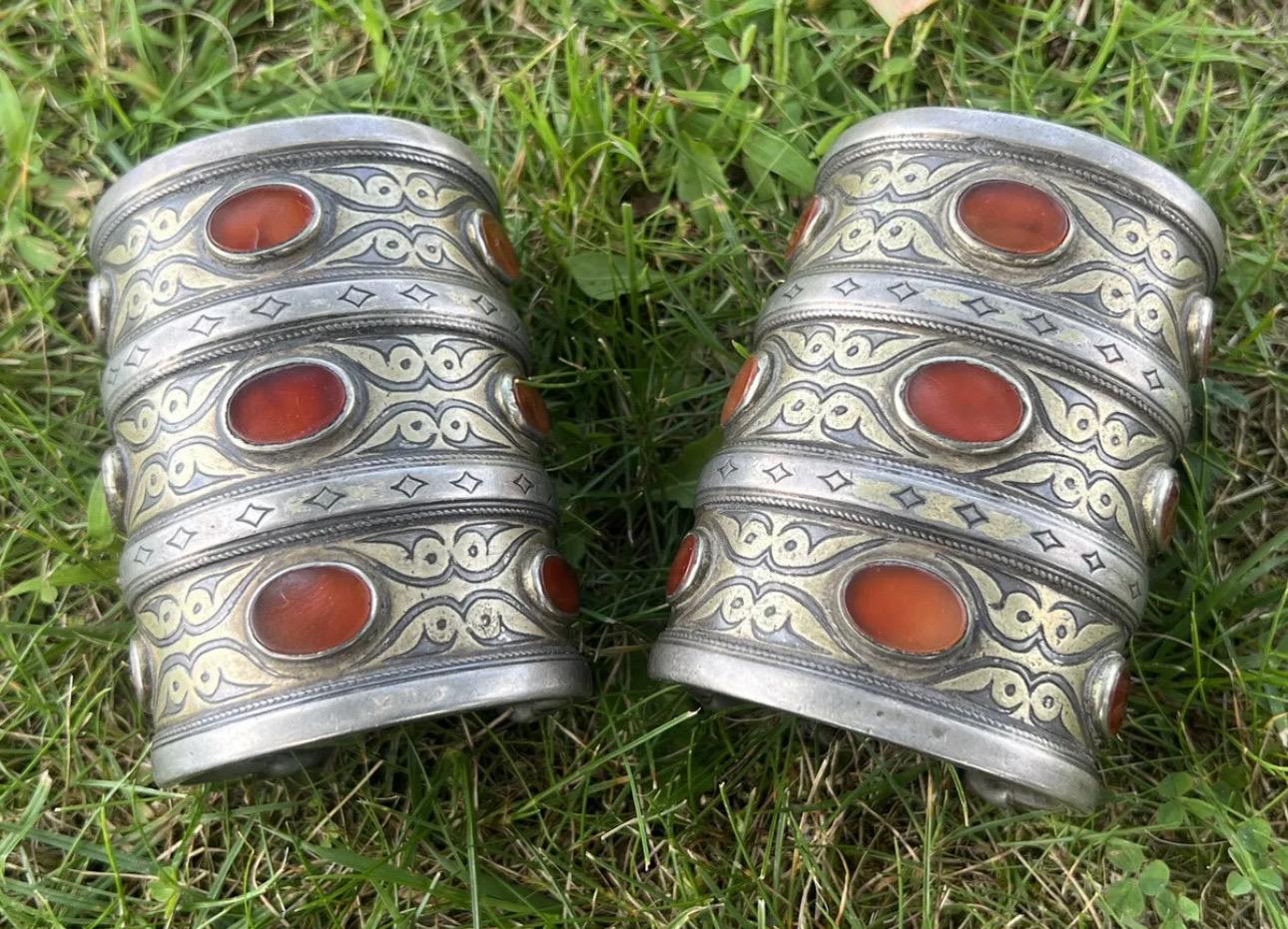 This is a unique and beautiful set of two old Tekke Carnelian tribal Turkoman Turkmen silver cuff bracelets. The intricate handmade design showcases the Middle Eastern and ethnic style of the piece. The bracelets feature stunning orange Carnelian