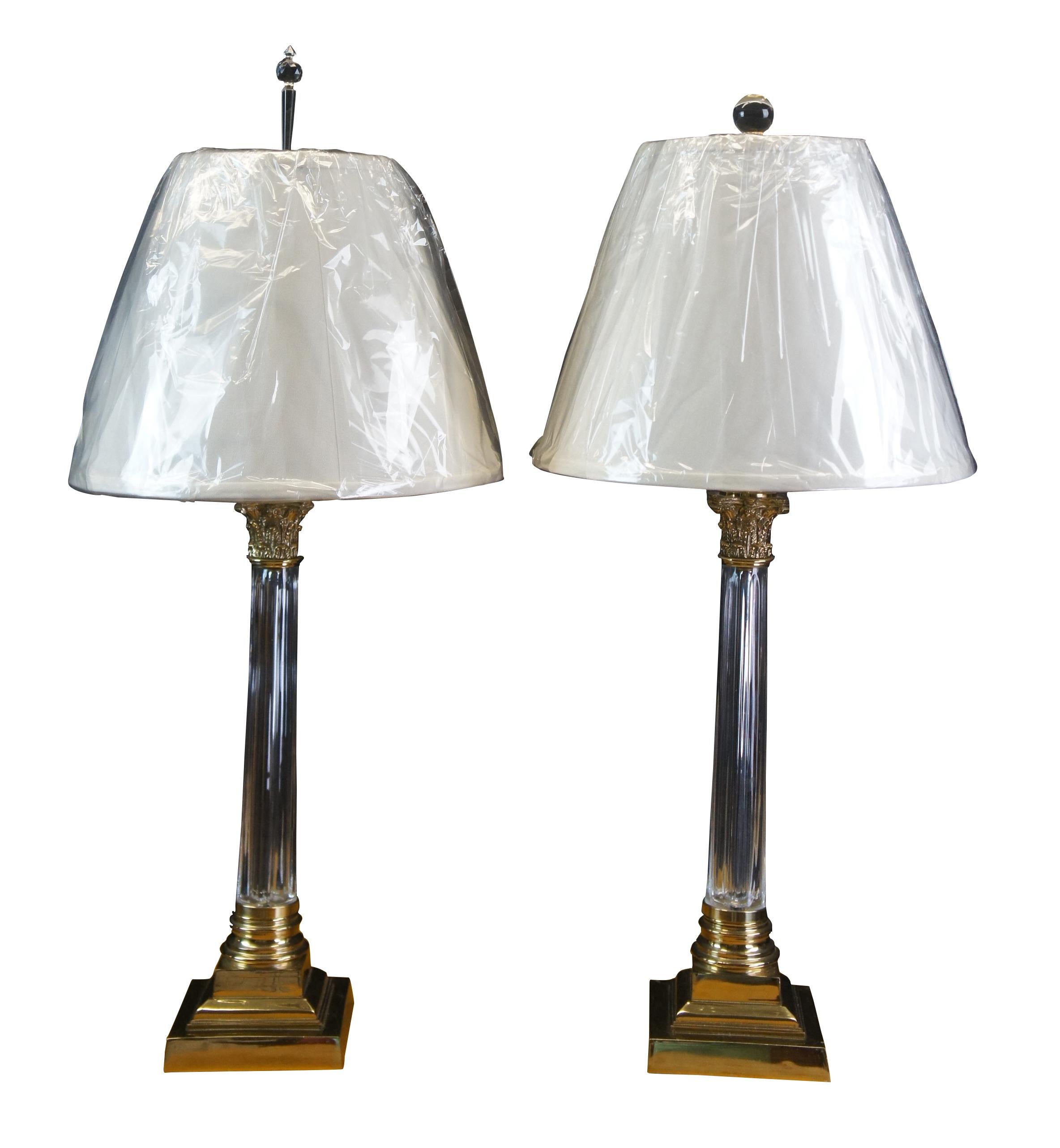 Pair of early Corinthian column table lamps by Scully & Scully. Made from brass with crystal cylinders. Includes a pair of unopened lite top lamp shades. 

Measures: 5.5