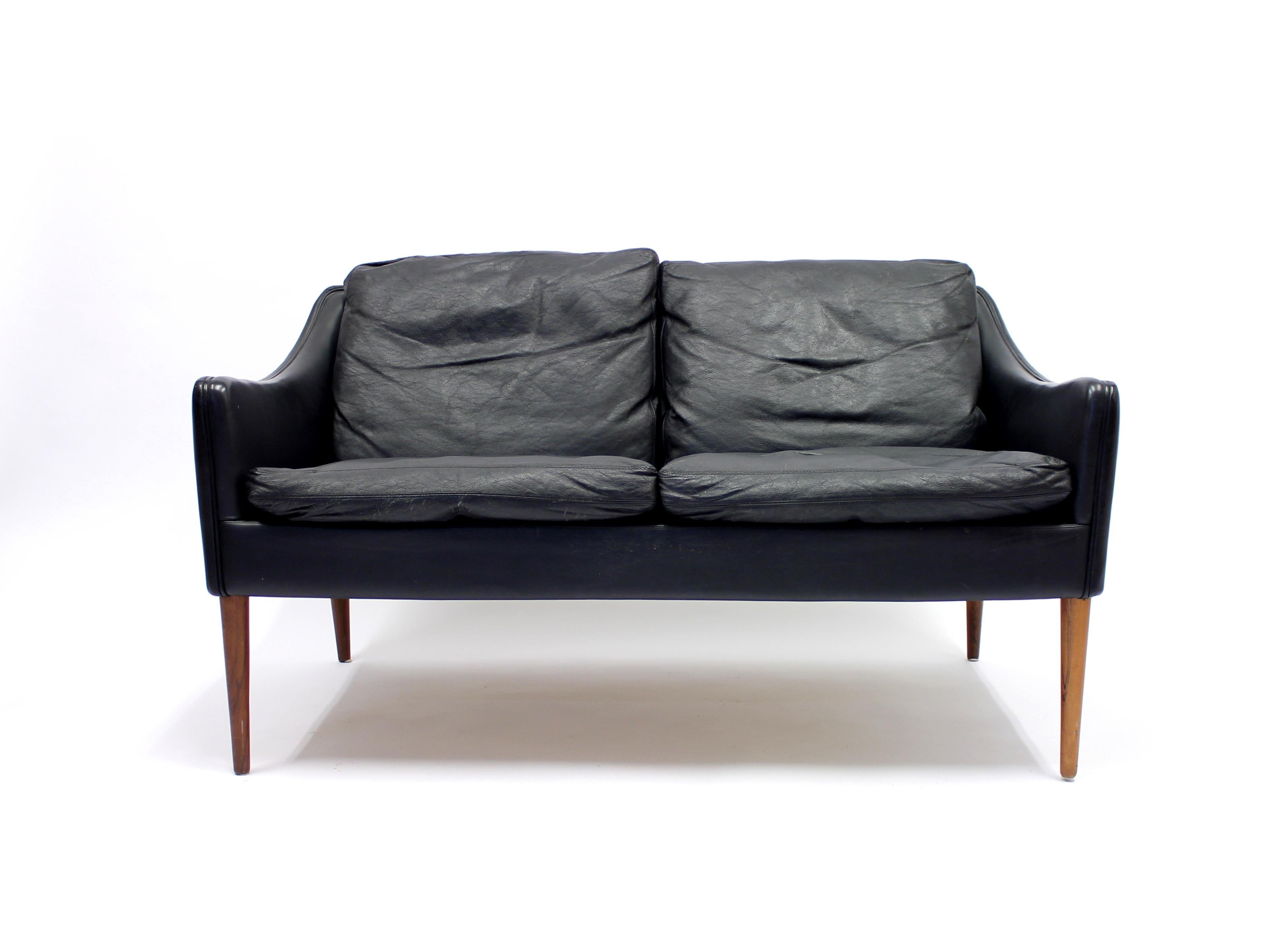 Black leather sofa on rosewood legs designed by Hans Olsen for CS Møbelfabrik in the 1960s. Normal patina consistent with age and use. Original condition. On the outside of the right arm rest occurs a bit of ware that has been professionally