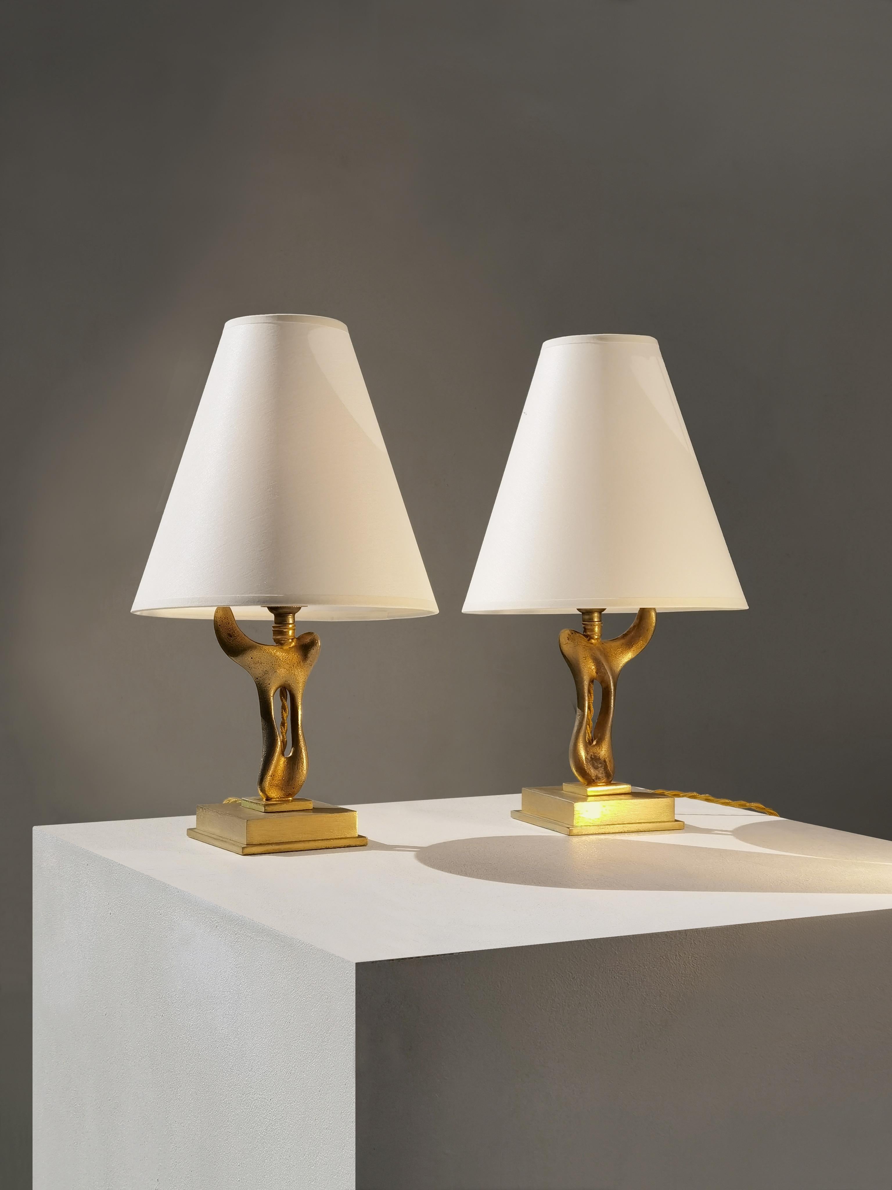Un precioso y encantador par de lamparitas de forma libre, perfectas para mesillas de noche alrededor de una cama o alrededor de un sofá... 
Cada pieza se basa en una base cuadrada y pesada de metal dorado, con ángulos rectos que contrastan con los