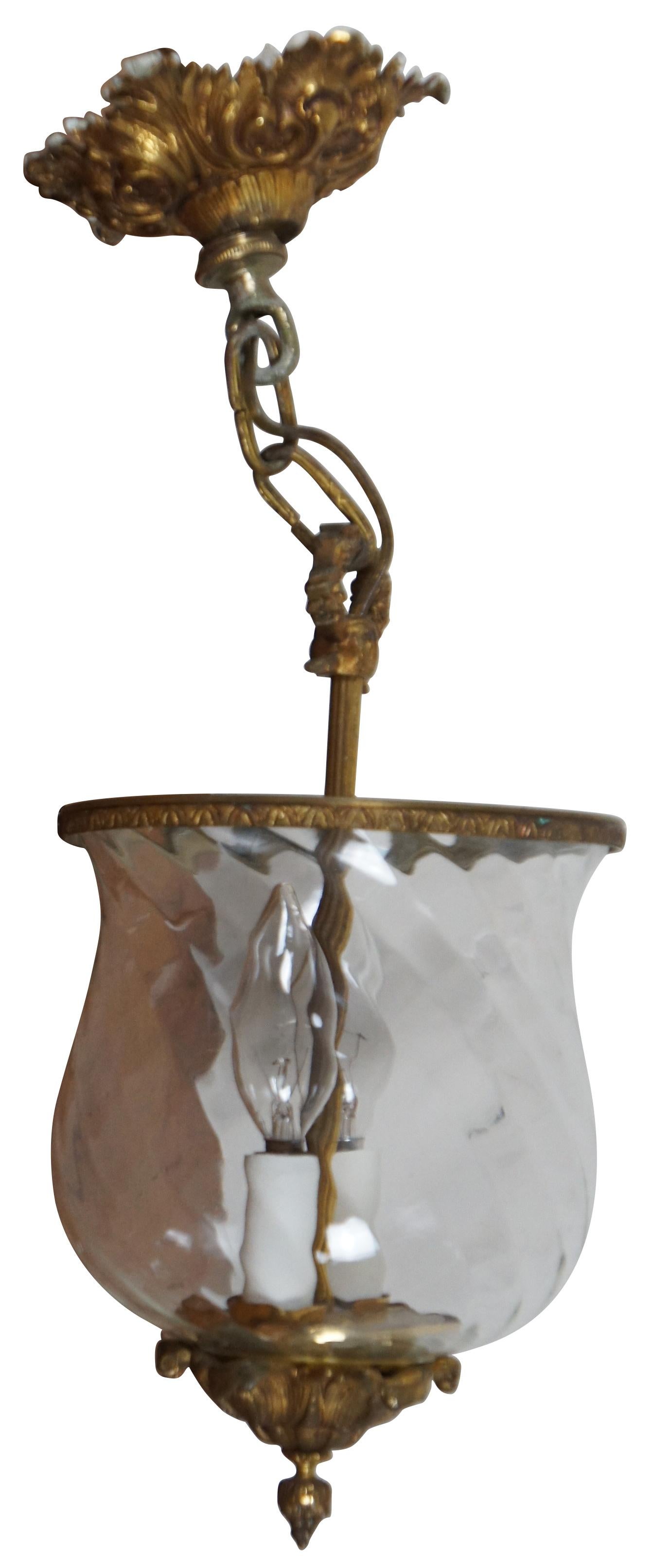Pair of vintage two light candle bell jar / lantern style pendant lights fashioned of glass hurricanes with a twisted, rippled design, with ornate baroque brass accents. Made in Spain.

Measures: 7.25” x 12” / chain length – 6” (Diameter x Height).