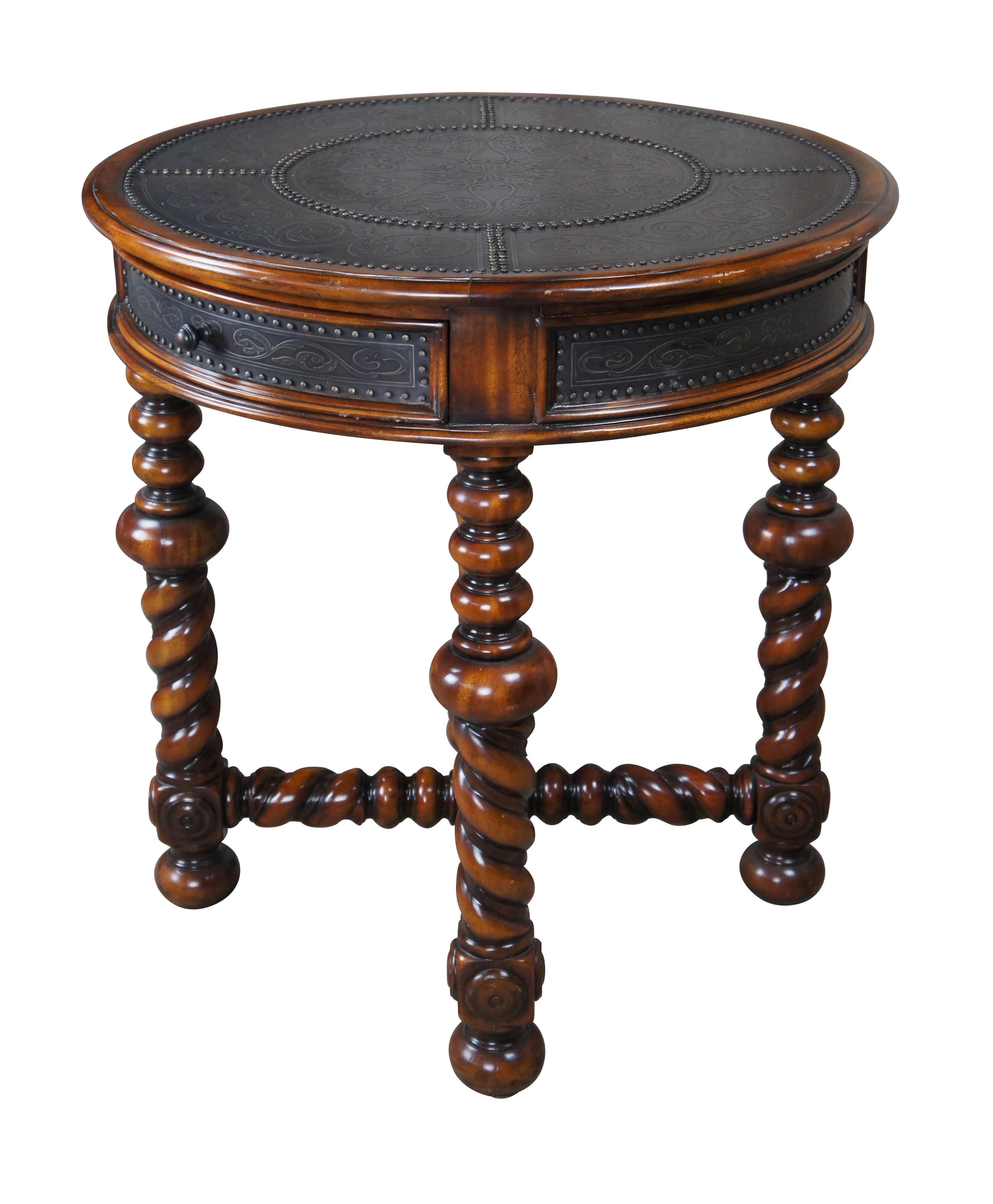 A solid mahogany and brass engraved circular lamp table by Theodore Alexander, Circa late 20th Century. Features a frieze drawer, on barley twisted turned legs and stretchers. Includes a turned lower trophy finial and riveted accents. The table is