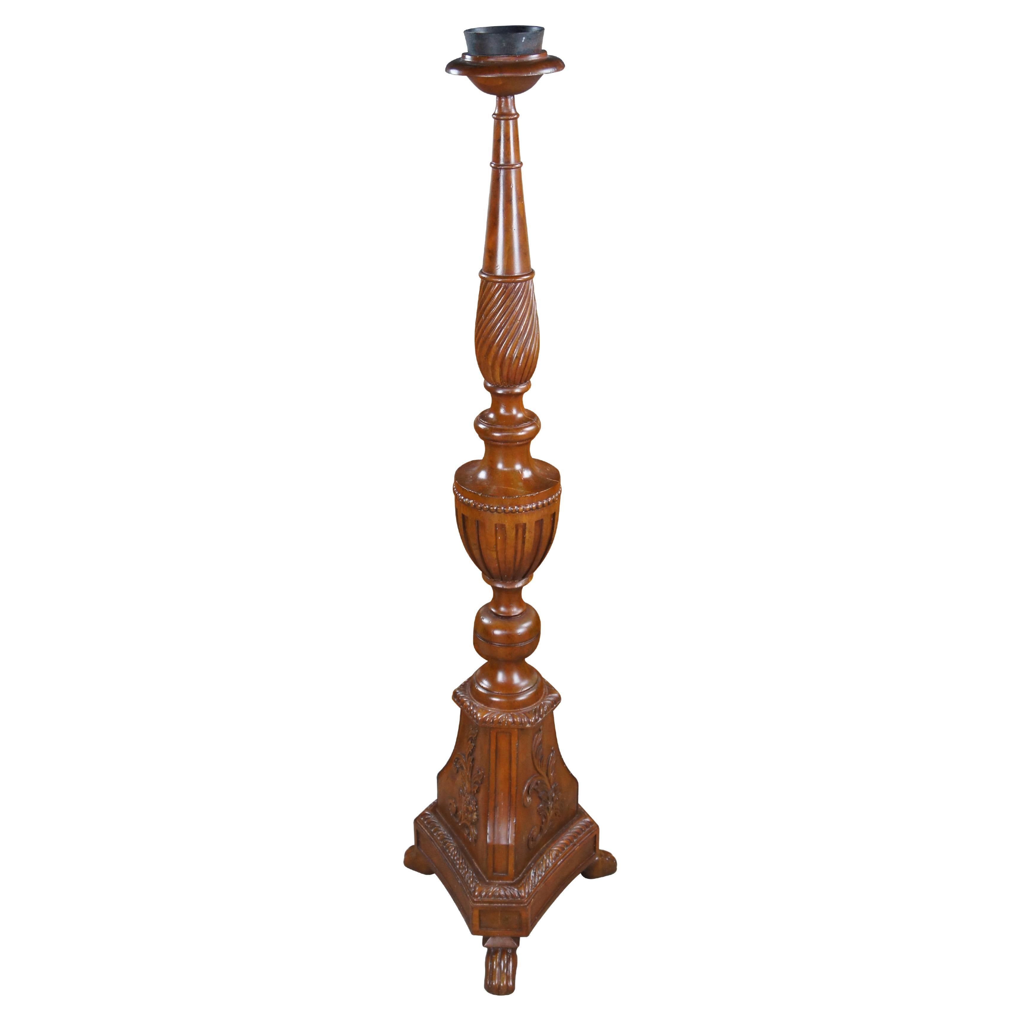 A stately pair of Theodore Alexander torchiere candle holders / altar sticks. Made from mahogany with a turned and graduated baluster with twisted, fluted and beaded accents. Features a tripod base with foliate carving over paw