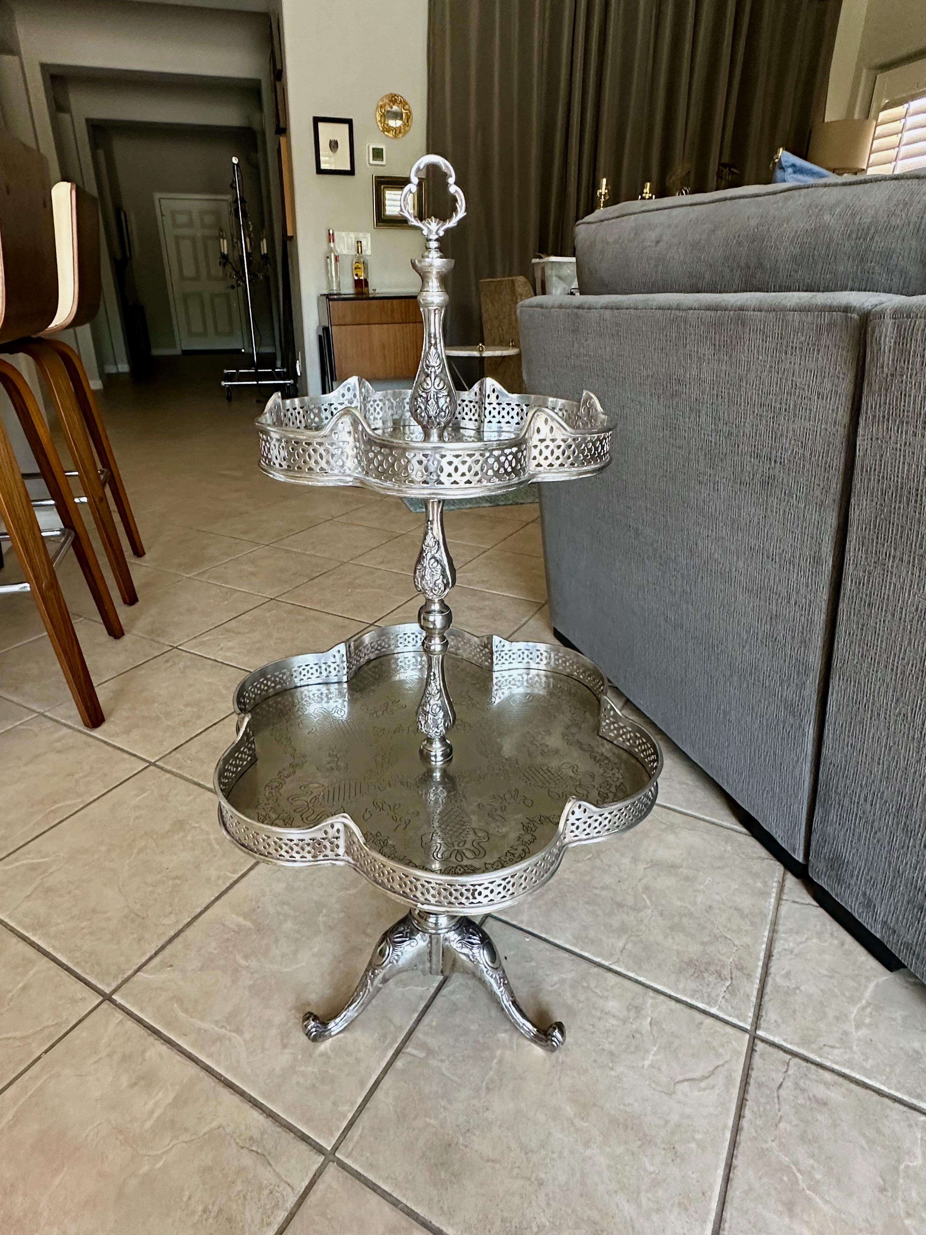 Unique French silverplate two-tier etagere food or beverage display table. Nice detailing throughout including tripod curved legs, reticulated gallery rails, and decorative engraving on each of the shelve surfaces. Can be used for array of display