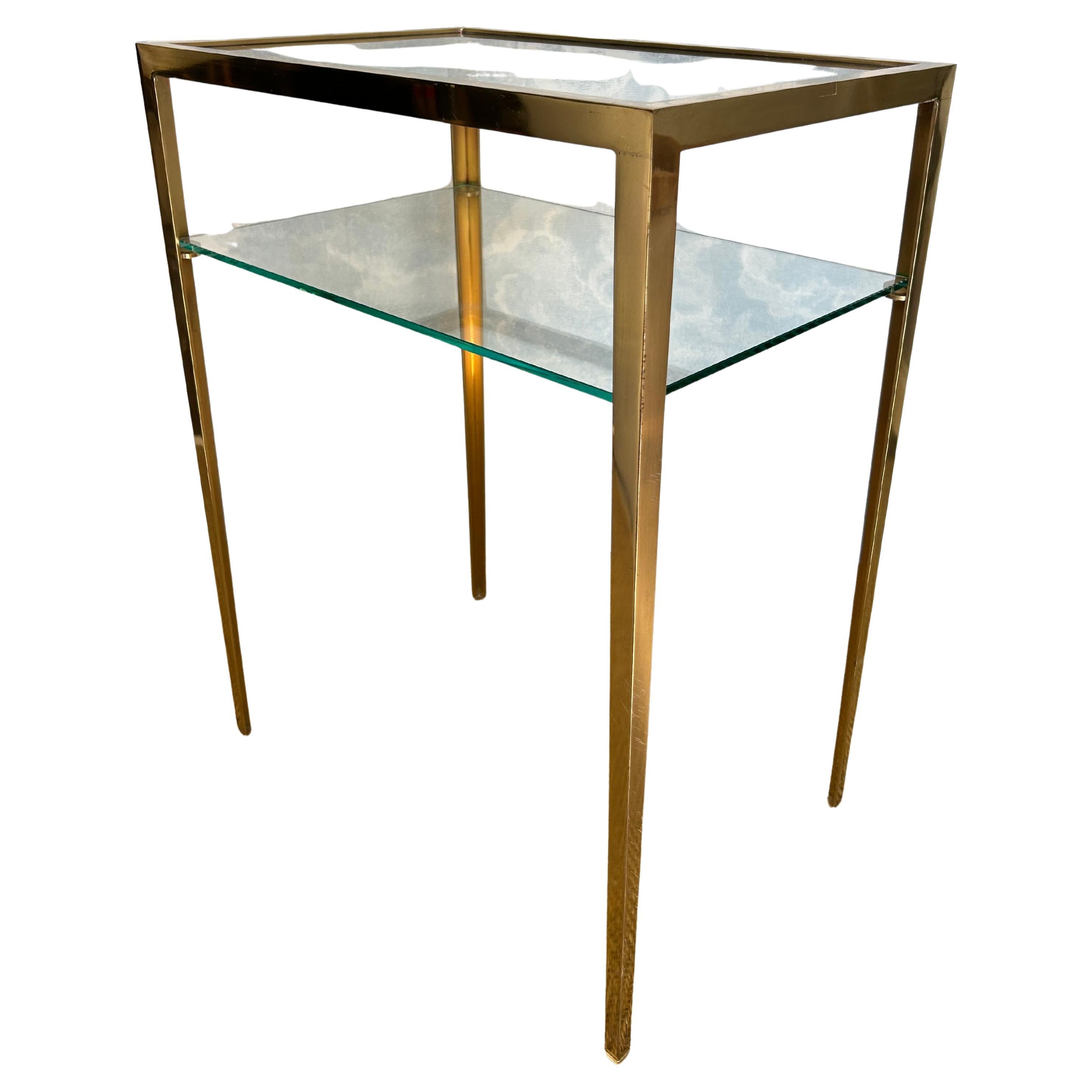 Reduced to the essential, balanced, and well-proportioned, this 2-tiered side table has an air of understated elegance!

It is composed of a shiny brass frame, which holds two rectangular clear-glass shelves. 

While showing some slight scratches on