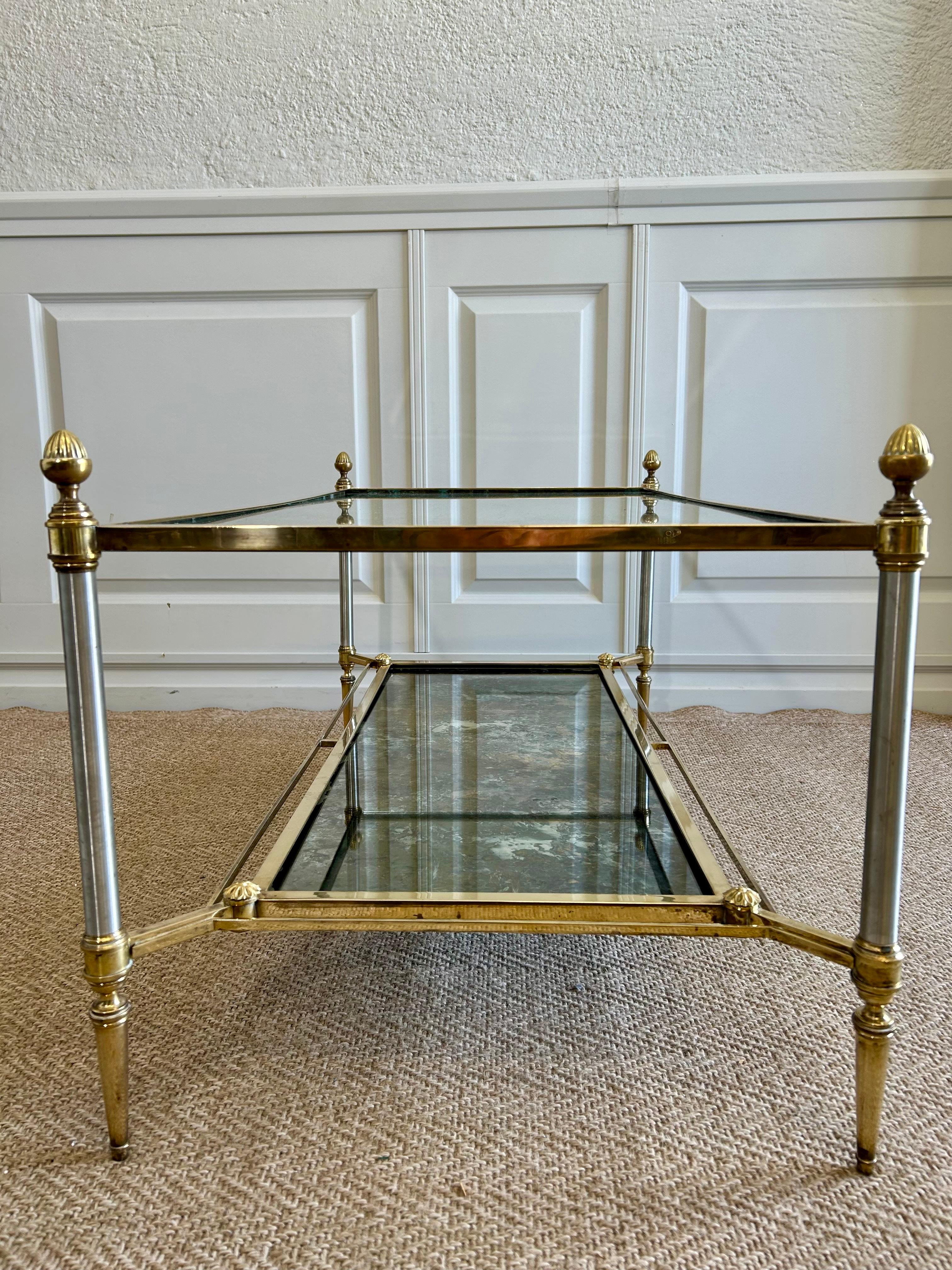 This two-tiered coffee table with elegant lines and beautiful detail, is a delightful piece of furniture by the most sought after design house Maison Jansen in Paris!

With a clear glass upper shelf and a reflective treated metal (possibly eglomise)