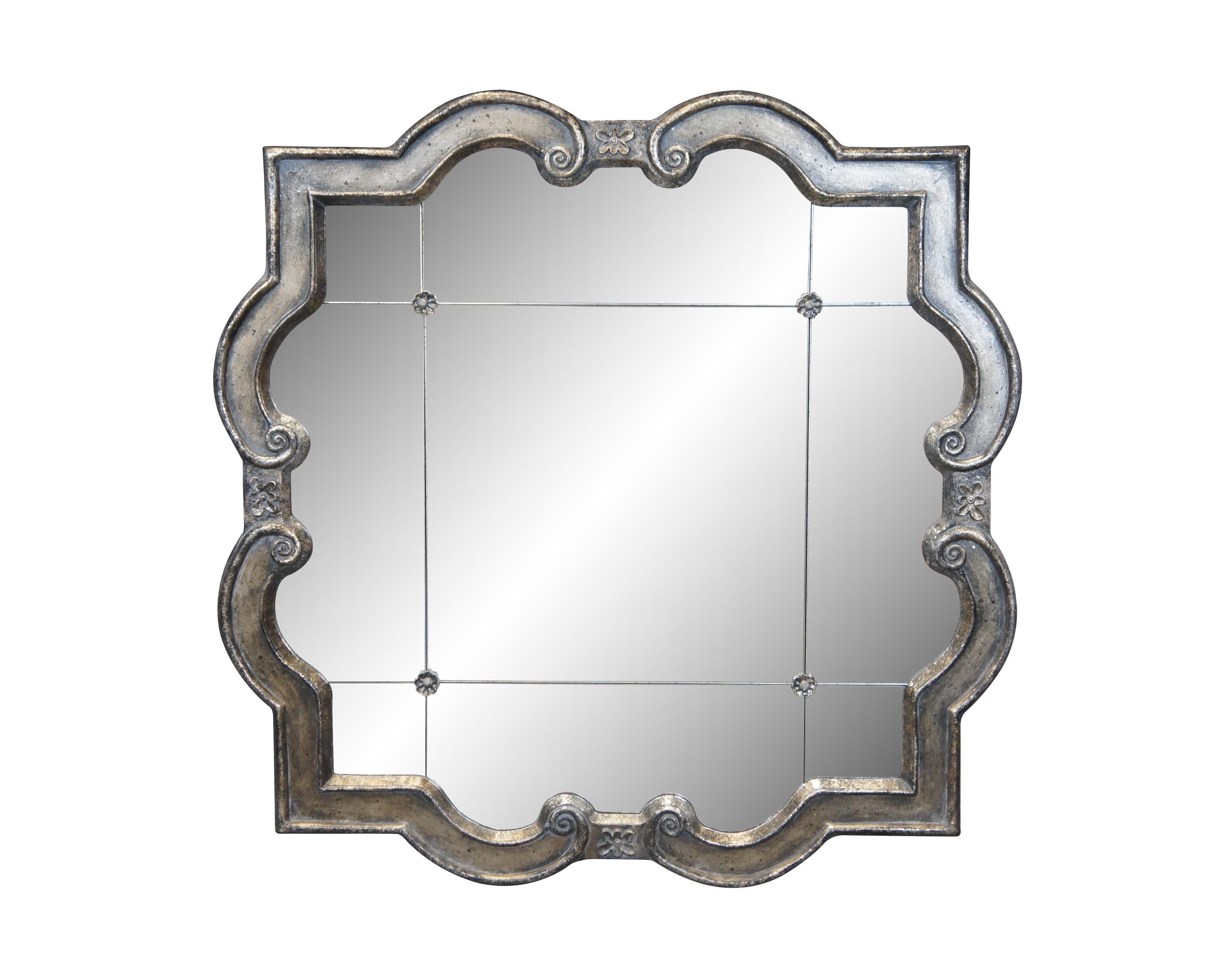 Pair of Uttermost model number 12597 P Prisca quatrefoil wall mirrors. Features a paneled architectural design studded with four rosettes and simulated silver loss, framed in antique silver gilt with scrollwork and floral details. Discontinued